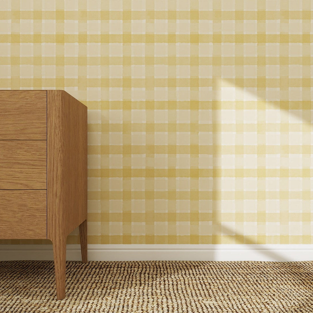 A wooden dresser with three drawers stands on a woven rug beside a yellow Checkered Wallpaper Repeat Pattern, highlighting the vibrant wallpaper color as sunlight casts a shadow from the right.