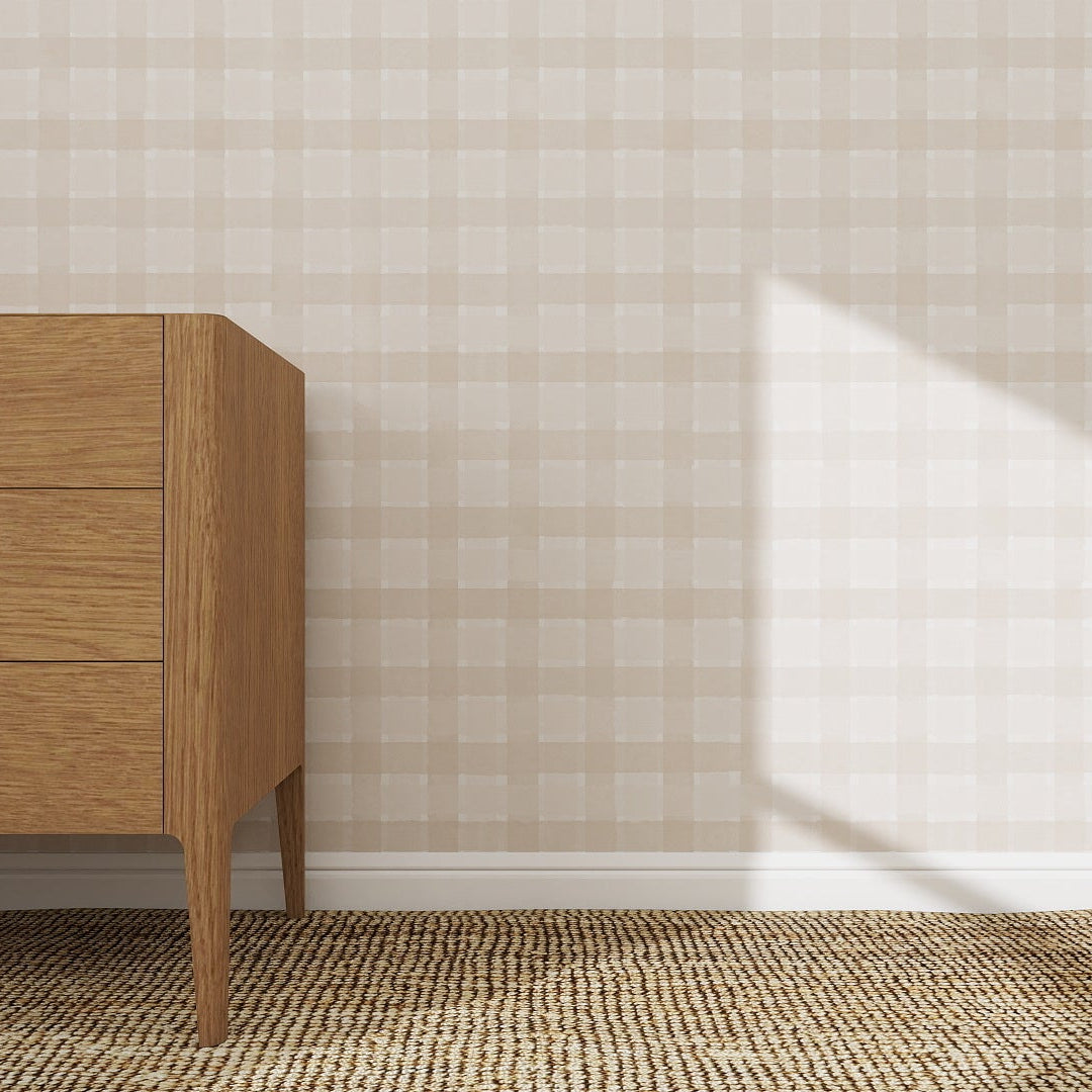 A wooden dresser stands on a woven rug against the Checkered Wallpaper Repeat Pattern Cream, its refined plaid design highlighted by sunlight casting geometric shadows and enhancing the room’s bright, minimalist appeal.