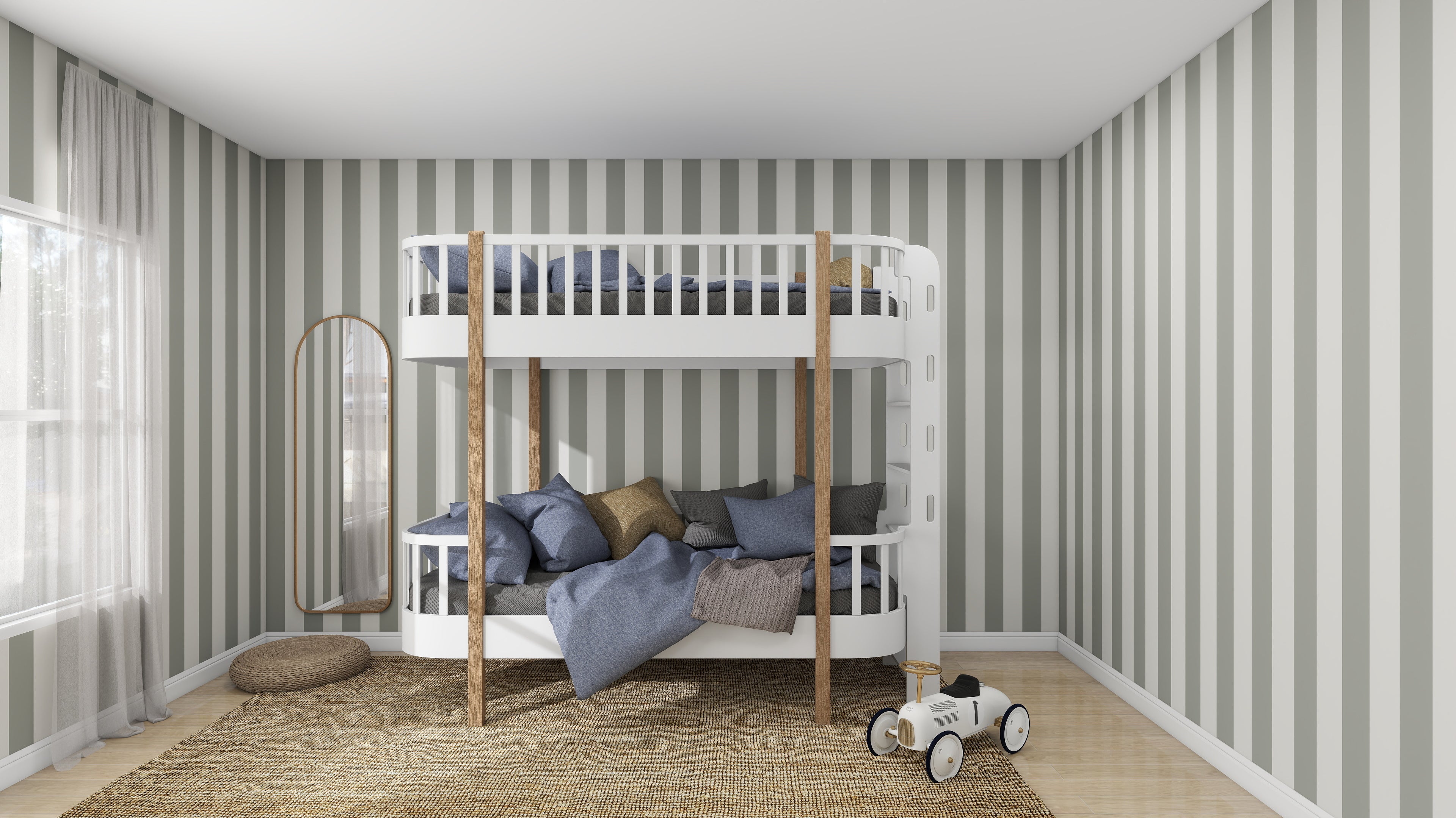 A minimalist kids space includes a white and wood bunk bed with gray and blue bedding, Circus Stripe Wallpaper Matcha by munks and me, a large window with sheer curtains, a woven rug, a round cushion, a toy car, and an oval mirror.