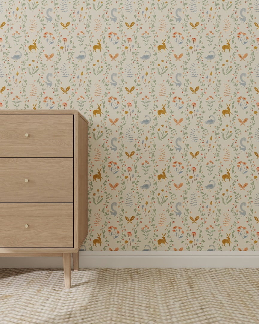 A light wood dresser with six drawers stands on a beige patterned carpet. Behind it, Coles Berry Patch Wallpaper displays whimsical leaves and flowers on a cream background. Sunlight streams in from the left.