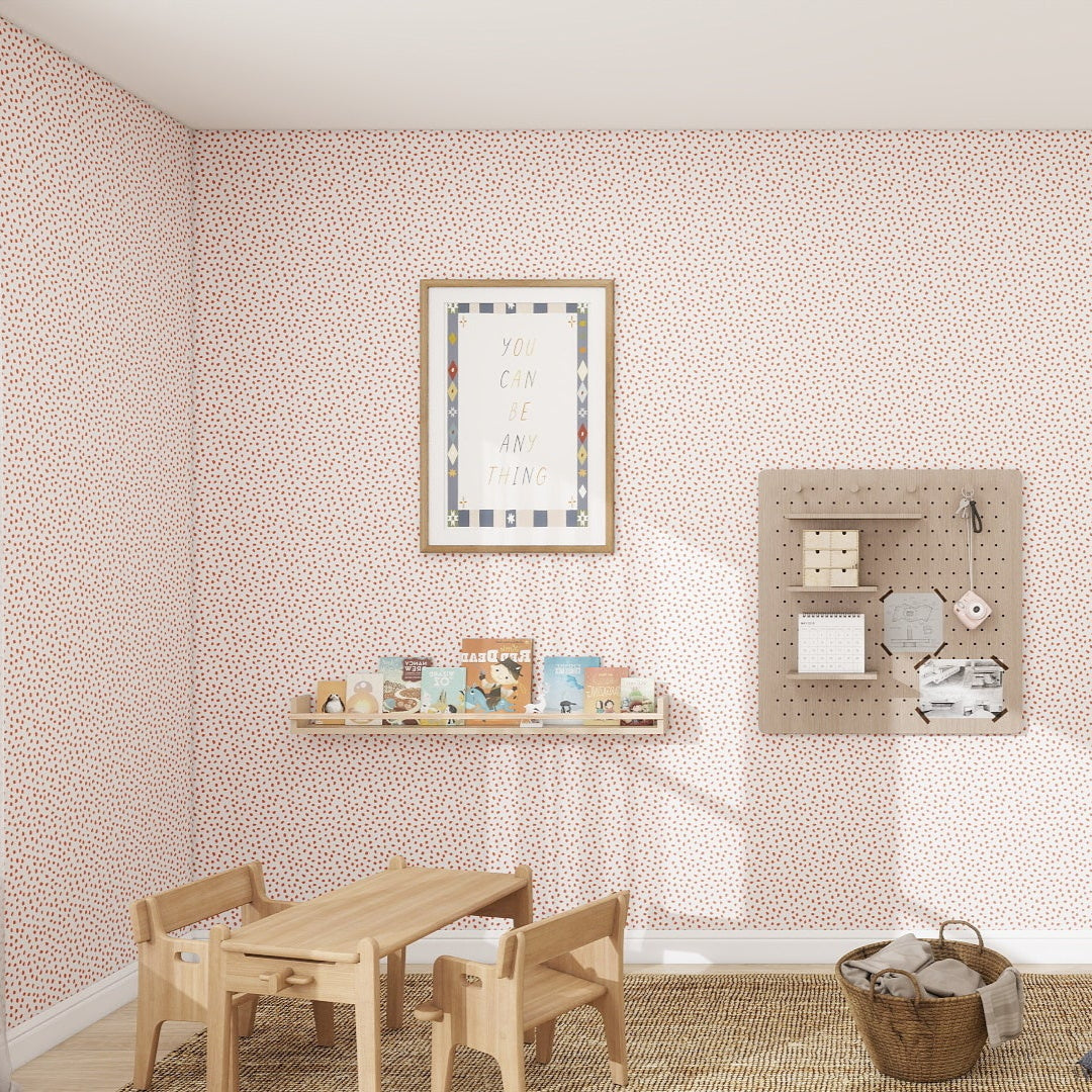 A childs room includes a small wooden table and chairs on a woven rug, surrounded by Cherry Red Sprinkle Wallpaper samples. Decor adorns the walls, with a framed poster, colorful shelves for toys, and a pegboard. A closed wardrobe sits on the right with an adjacent mirror.