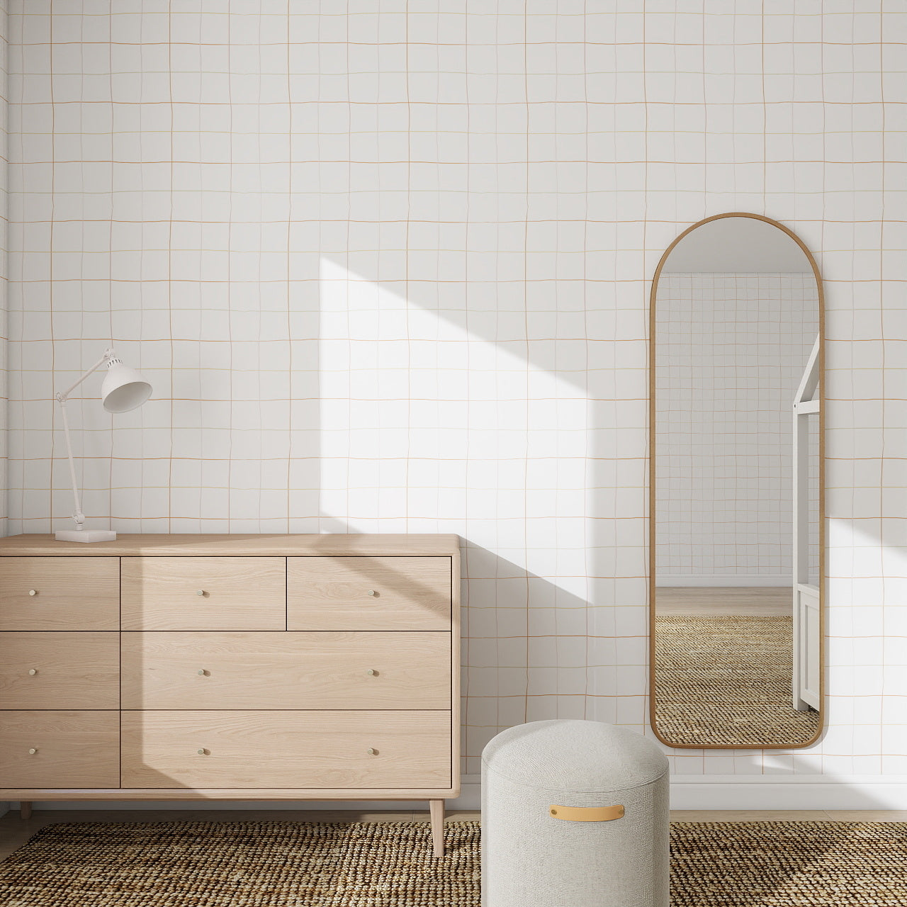 A minimal bedroom with a light wood dresser, arched mirror, gray ottoman, and desk lamp features modern decor. Sunlight casts geometric shadows on the Doodle Grid Wallpaper Repeat Pattern for a subtle, stylish effect.