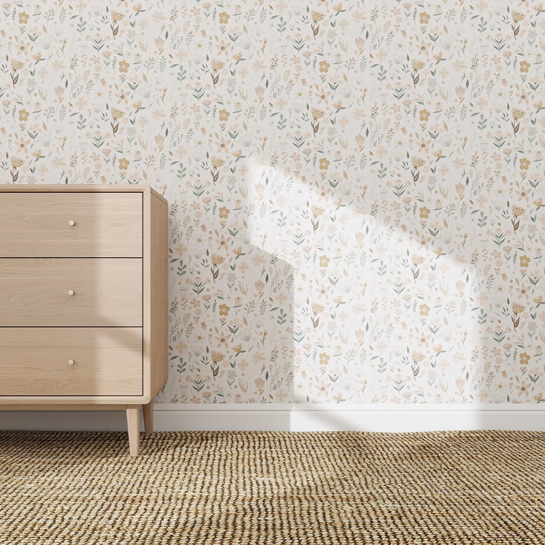 A light wooden dresser with six drawers stands against a wall covered in Millie Floral Wallpaper Repeat Pattern. Sunlight creates a shadow on the wall, and the floor features a woven, textured rug.