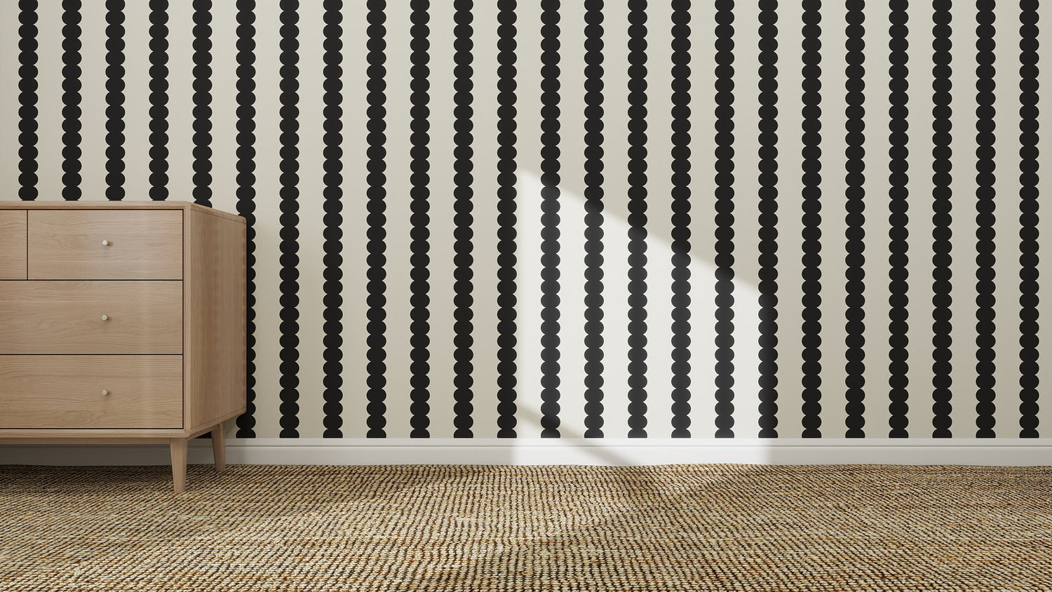 A wooden dresser stands against a wall adorned with Scallop Stripe Wallpaper Charcoal, next to a woven carpet, as sunlight casts a diagonal shadow across the wall.