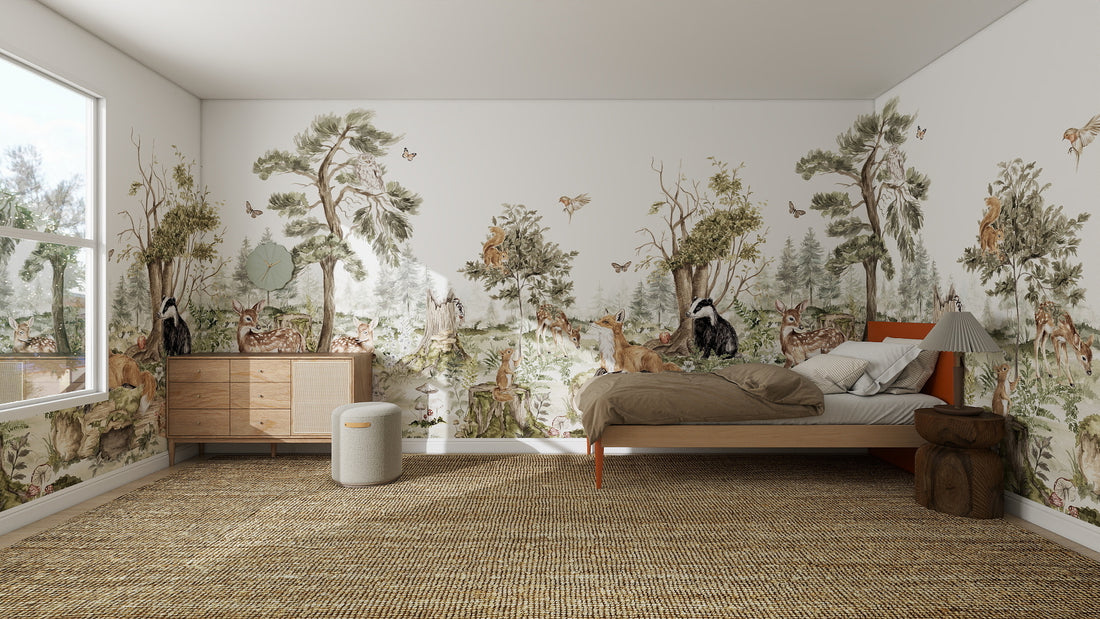 A cozy bedroom features the Into The Forest Wallpaper Mural | Sample with woodland trees, deer, foxes, and birds. The room includes a bed, wooden dresser with mirror, window, and a woven rug on the floor.