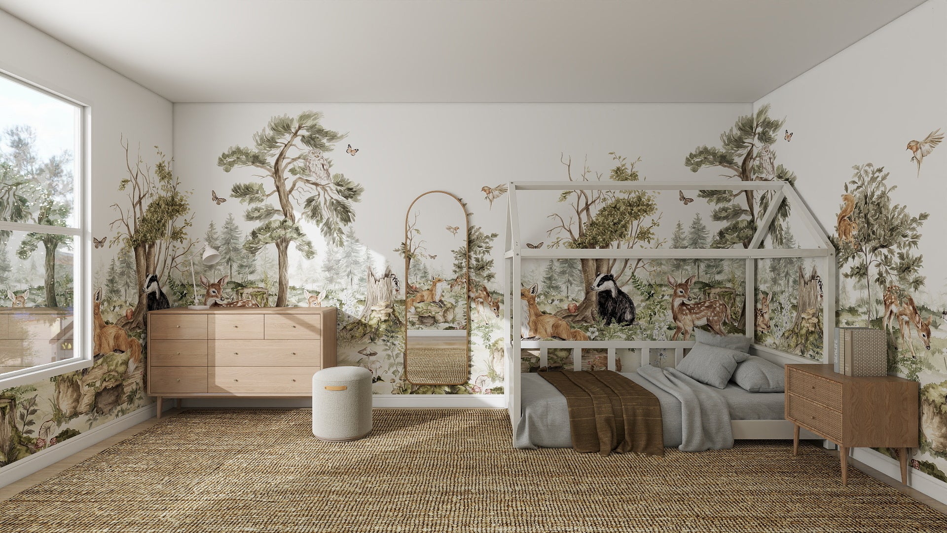 A childrens bedroom with the Into The Forest Wallpaper Mural featuring woodland trees and animals, a house-shaped wooden bed frame, light wood dressers, a wicker basket, a round laundry bin, and a large sunlit window.