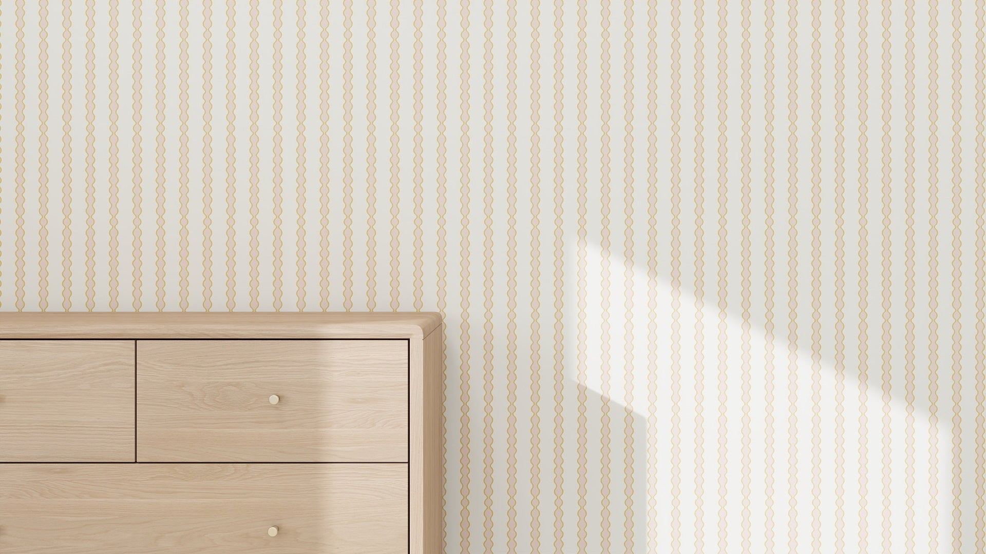 A light wood dresser with three drawers sits against a cream wall decorated with the Little Abacus Stripe Wallpaper Sample in Pink and Yellow. Sunlight casts a diagonal shadow, highlighting the quality and airy feel of the space.