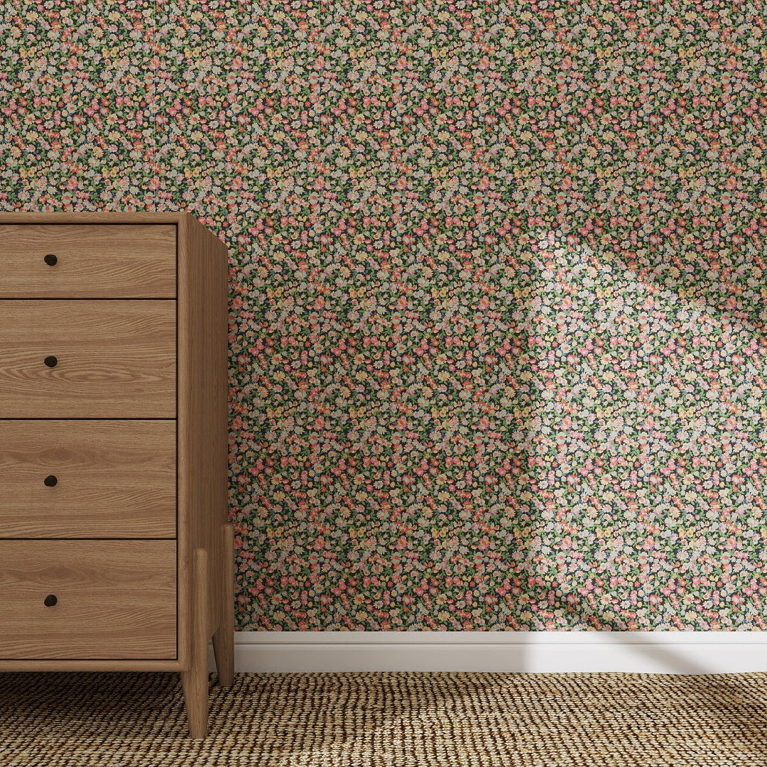A wooden dresser with four drawers stands against a wall adorned with Midnight Meadow Florals Wallpaper. Sunlight casts a triangular shadow, highlighting the wallpaper’s pattern and creating shapes on the carpeted floor.