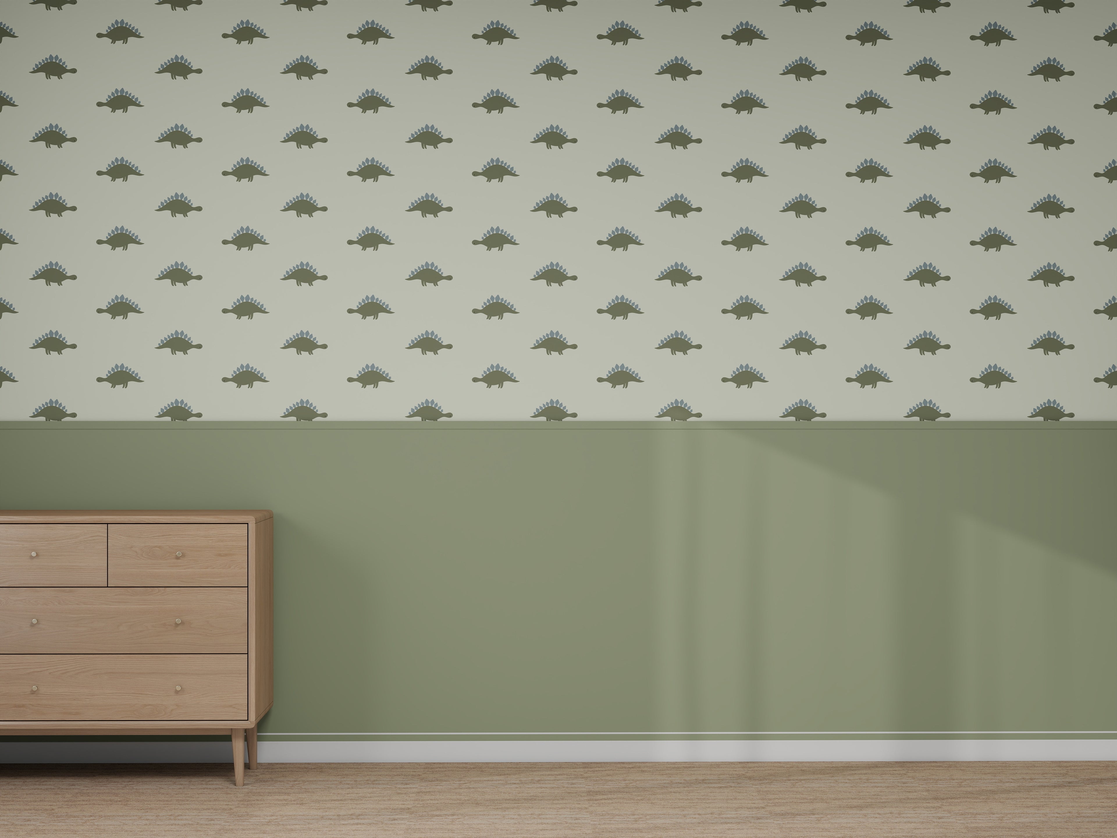 A room with light green walls, a wooden dresser on the left, and the Custom Otis Dinosaur 1 | Sample wallpaper above solid green wainscoting. The light brown wood floor perfectly complements the playful wallpaper color.
