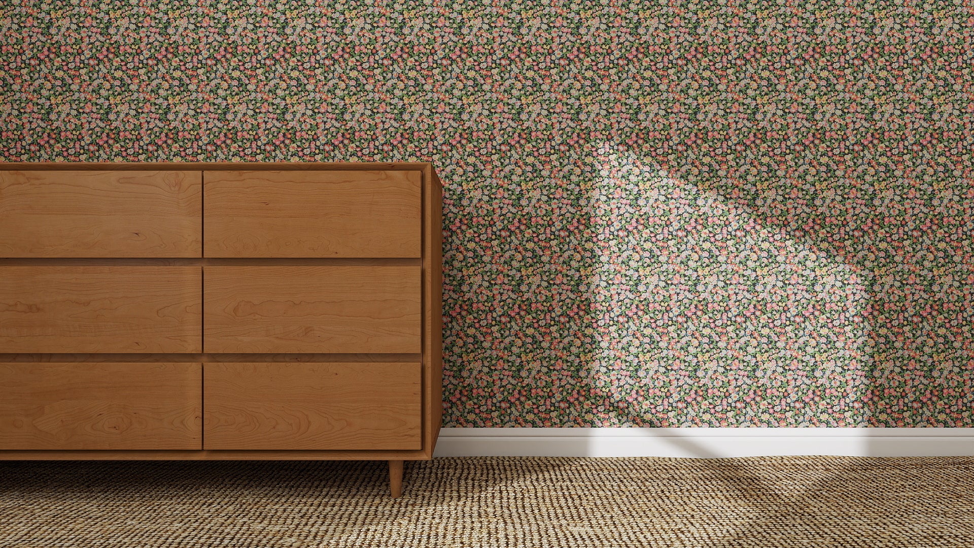 A wooden dresser stands by a wall covered in Midnight Meadow Florals Wallpaper | Sample, highlighting its vibrant colors. Sunlight casts an angular shadow across the wallpaper, while a woven carpet lies on the floor.