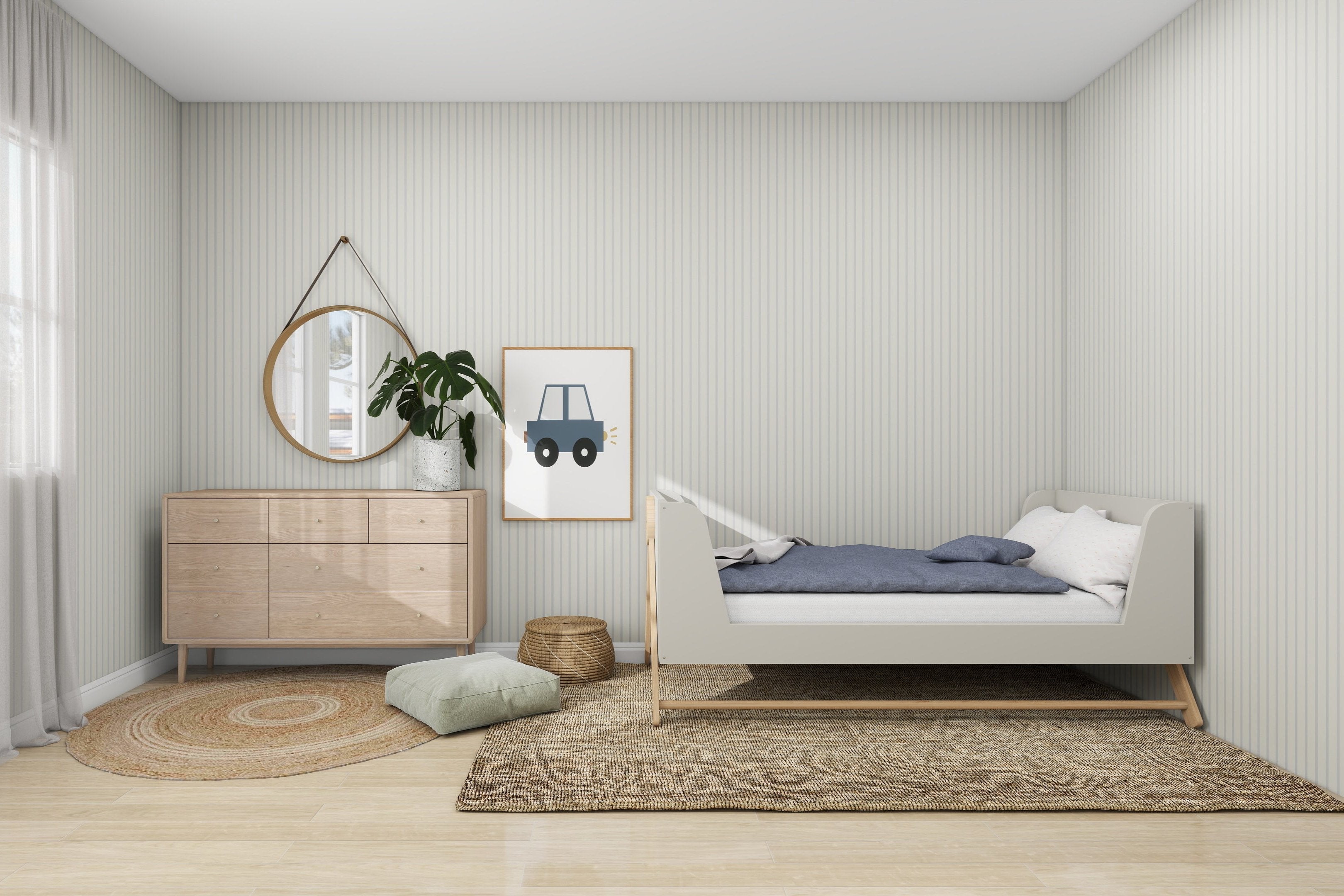 A minimalist bedroom boasts a light gray bed with blue bedding and pillows. Next to the framed car print, a wooden dresser supports a round mirror and plant. The light wood floor features a wicker basket, green cushion, and woven rugs, with walls adorned in munks and mes Pinstripe Wallpaper Sky.