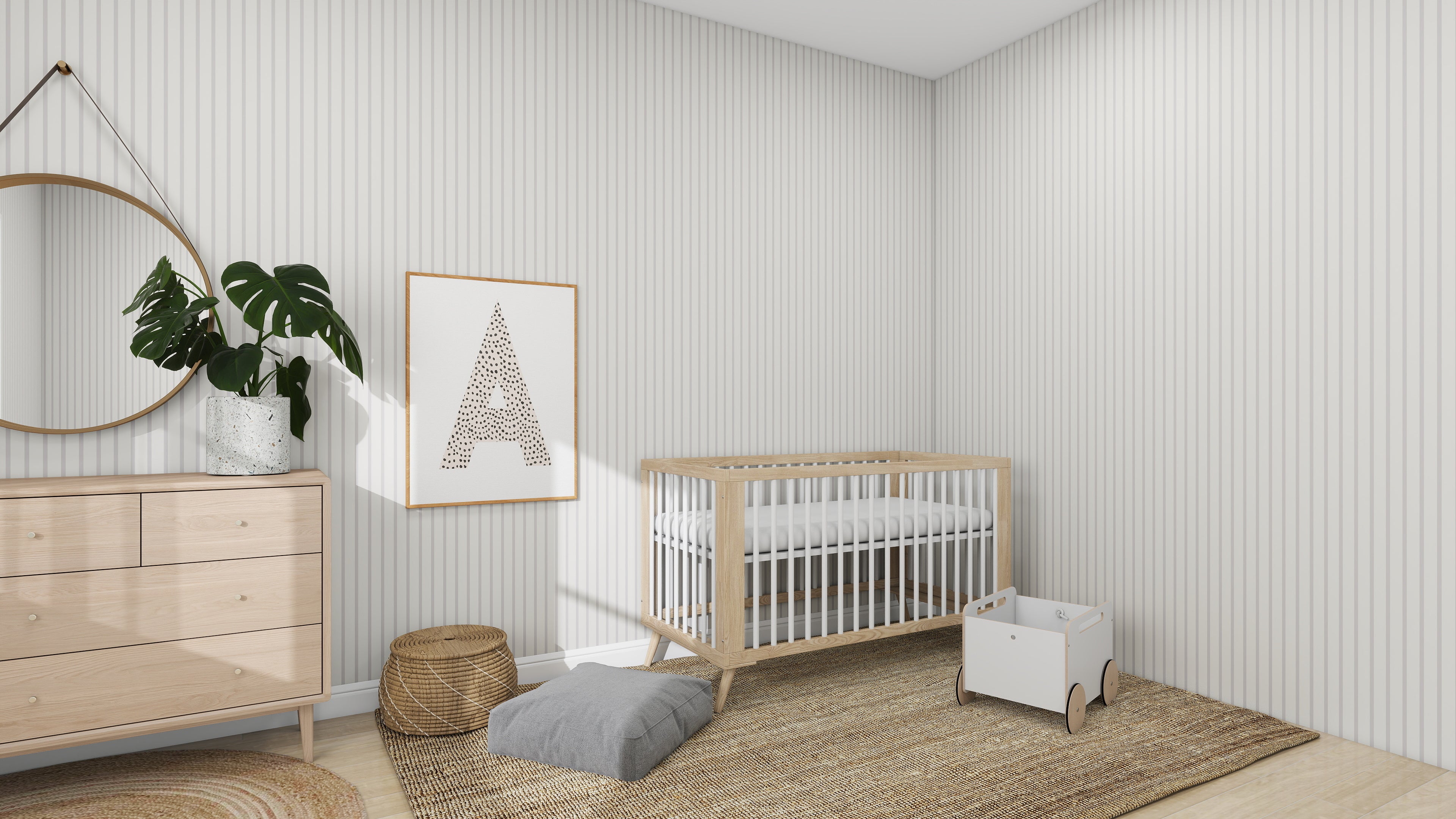 A minimalist nursery includes a light wood crib, a dresser topped with a round mirror, and a large framed letter A. A plant, woven basket, cushion, and toy cart sit on the rug. The walls boast munks and mes Pinstripe Wallpaper Soft Beige for added elegance.