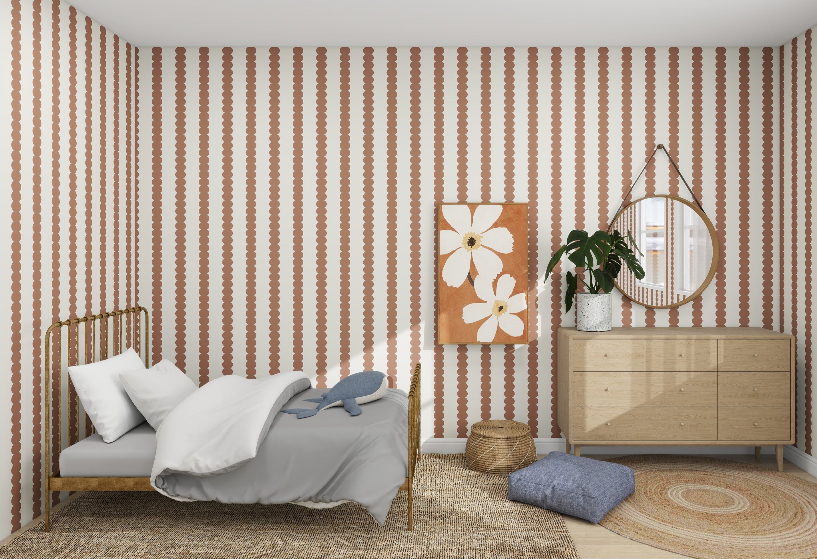 The cozy bedroom features a single bed with white and gray bedding, charming pink and white Scallop Stripe Wallpaper Mocha by munks and me on the walls, a round mirror, floral artwork above a wooden dresser, along with a potted plant, wicker basket, and rug to complete the decor.