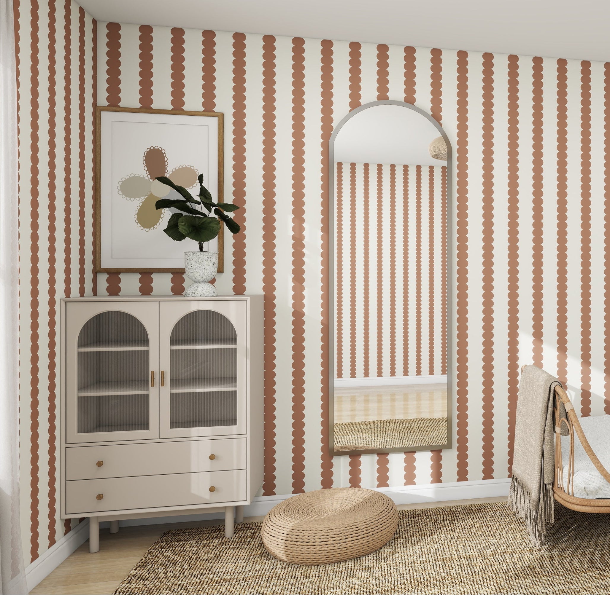 The room features a cabinet with glass doors, topped with a plant and artwork. An arched mirror hangs on the wall, perfectly paired with munks and mes Scallop Stripe Wallpaper in mocha. A woven rug and pouf on the floor add warmth to this inviting space.