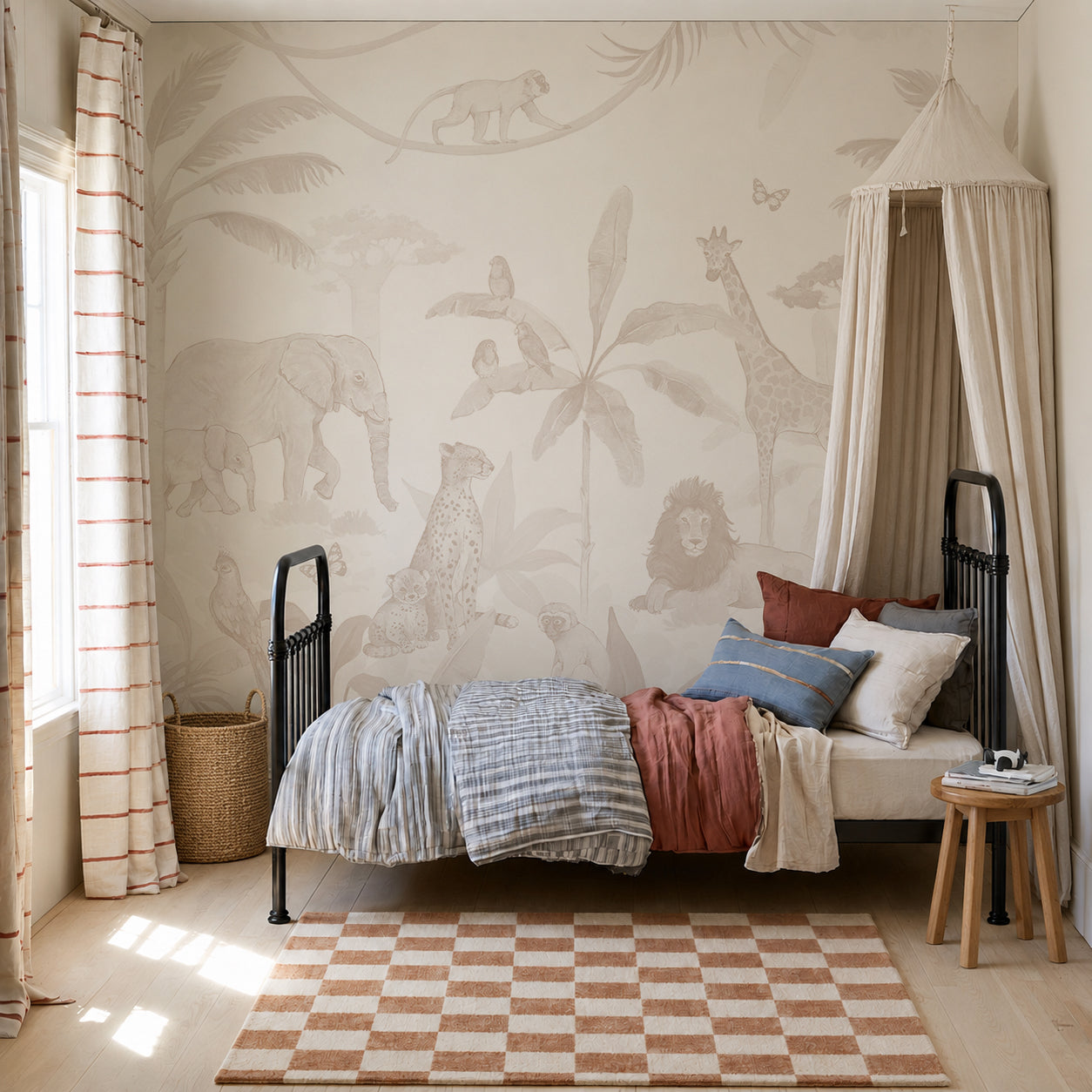 A cozy, light-filled children’s room features the captivating African Safari Mural, Neutral as wallpaper, a black metal bed with layered blankets, a striped rug, a round stool with cushions, a wicker basket, and a canopy draped in one corner.