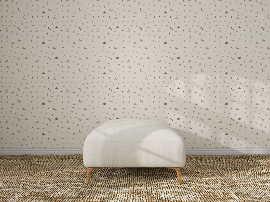 A simple white ottoman sits on a textured woven rug in front of Petite Circus Party Wallpaper, featuring a small, repeating floral pattern. Sunlight streams in, casting soft shadows on the wall and floor.