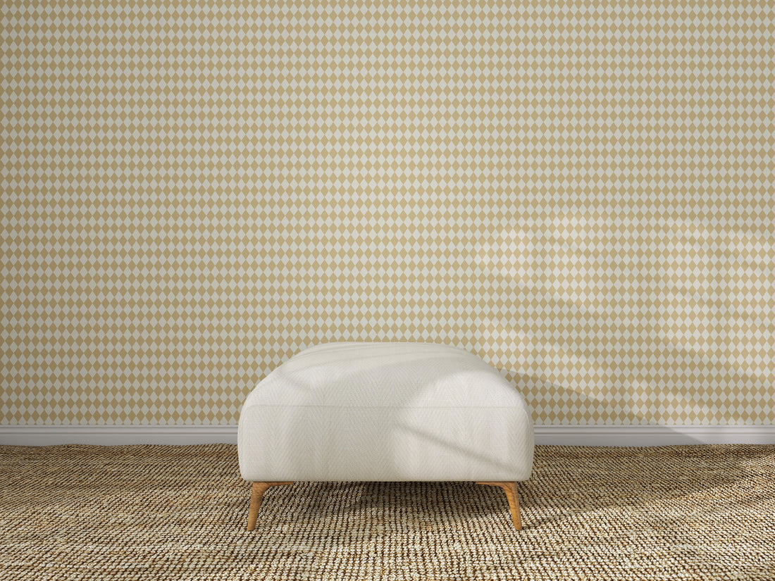 A white upholstered ottoman with wooden legs sits on a textured beige carpet in front of Diamond Dancer Wallpaper, Yellow. Sunlight casts soft shadows across the scene, highlighting the geometric diamond pattern.