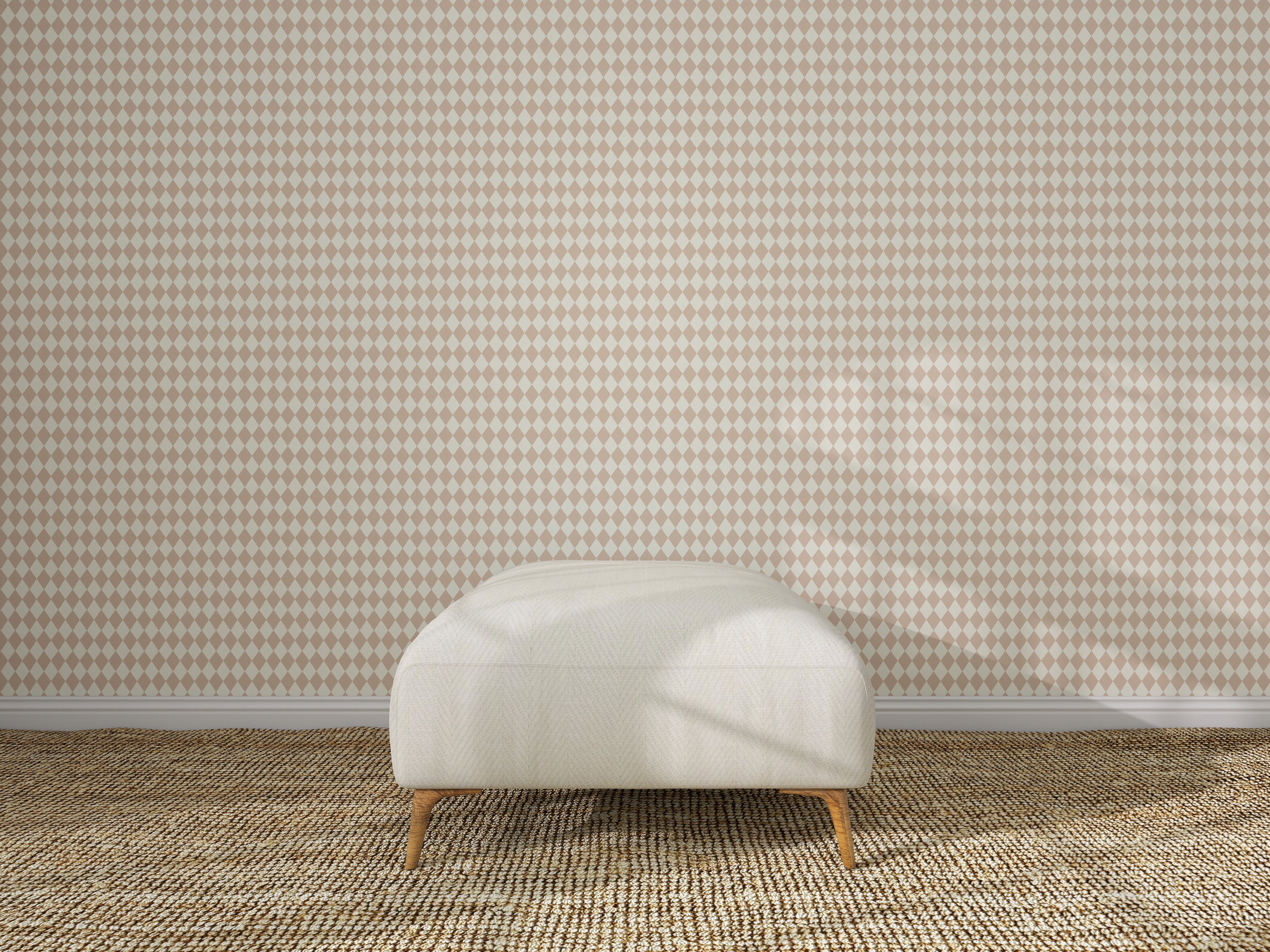 A beige ottoman sits on a woven carpet in front of a wall featuring the Diamond Dancer Wallpaper Sample in Rose. The empty, well-lit room has soft shadows on the wall and floor.