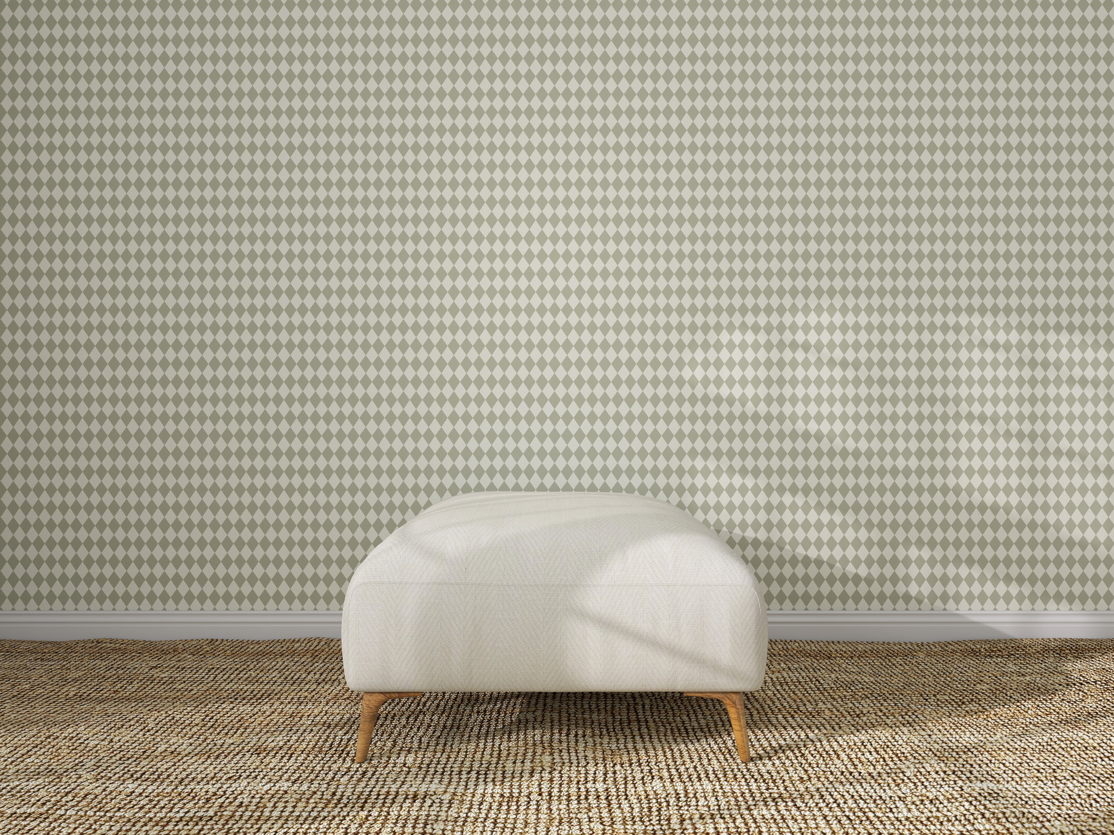 A cream-colored ottoman with wooden legs sits on a woven beige carpet, centered in front of a wall covered with Diamond Dancer Wallpaper, Green.