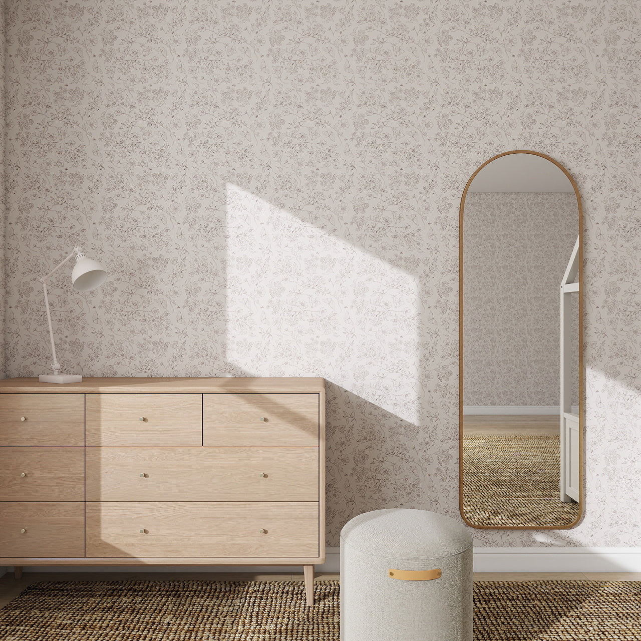 A minimalist bedroom corner with a light wood dresser, round ottoman, white desk lamp, large arched mirror, and Sunlit Meadow Wallpaper Repeat Pattern; sunlight highlights the wallpaper as it casts soft shadows on the wall and floor.