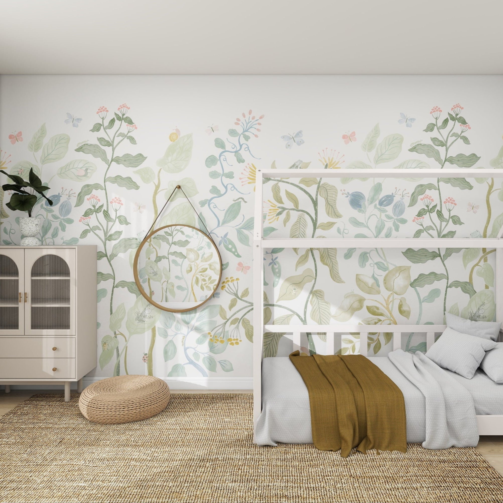 A cozy childrens room features a white house-shaped bed frame, beige rug, and brown throw blanket. The walls are adorned with the munks and me Secret Garden Wallpaper Mural. A glass-door cabinet with a round mirror is next to a woven pouf, with sheer curtains letting natural light create a whimsical atmosphere.