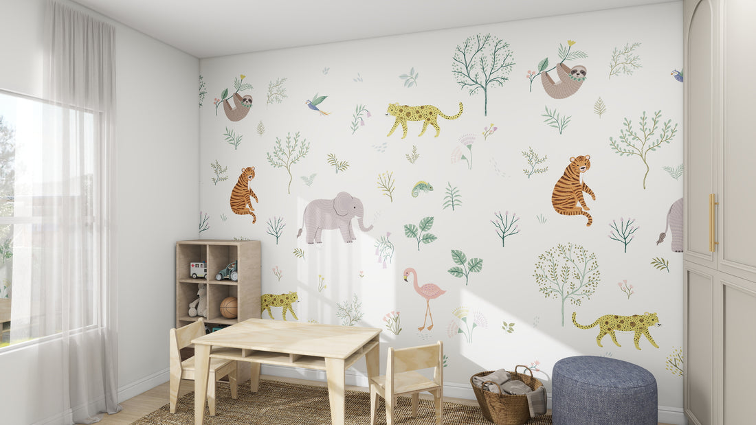 A childrens room with munks and mes Wild Wonders Wallpaper Mural showcasing tigers, elephants, sloths, and flamingos. A small wooden table with two chairs, bookshelves full of books, a cozy rug, and a basket complete the scene as sunlight streams through the window.