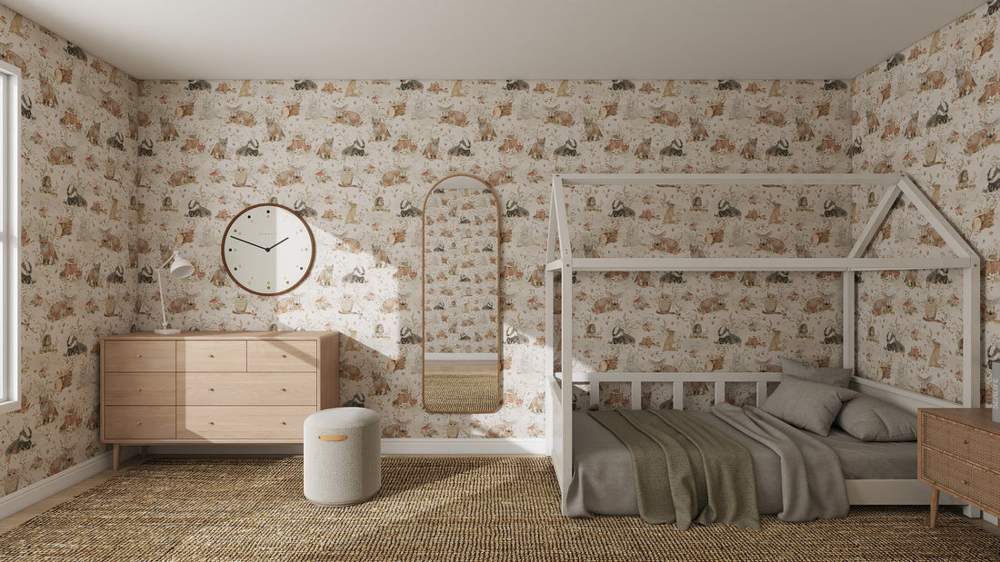 A cozy kids’ bedroom features Woodland Wonder Repeat Pattern wallpaper in playful colours, a wooden house-frame bed, green blanket, dresser with round mirror and clock, oval wall mirror, small ottoman, and woven rug.