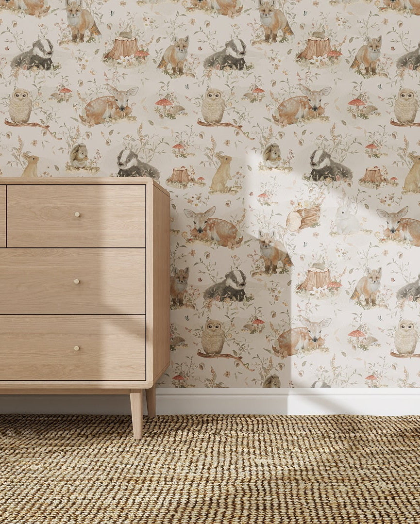 A light wood dresser stands on a woven carpet beside a wall adorned with the Woodland Wonder Wallpaper Sample, which features rabbits, flowers, and foliage in muted tones and showcases exceptional quality.