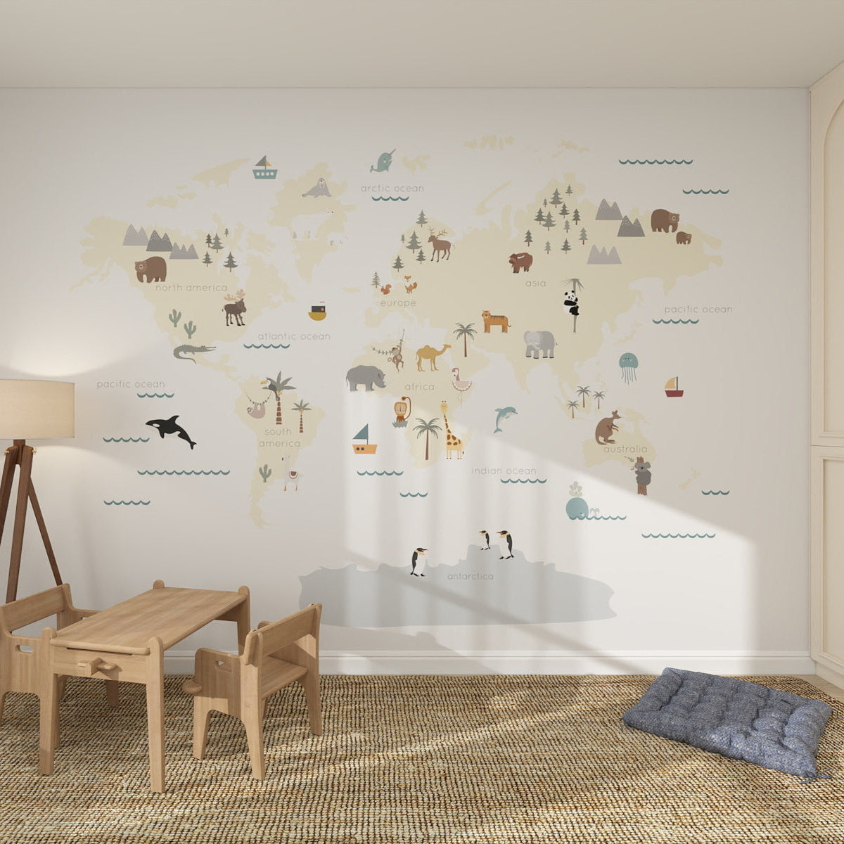 A children’s playroom with a wooden table and chairs, a soft rug, and the Character World Map Wallpaper Mural featuring illustrated animals for fun kids room decor. A blue floor cushion sits in the corner.