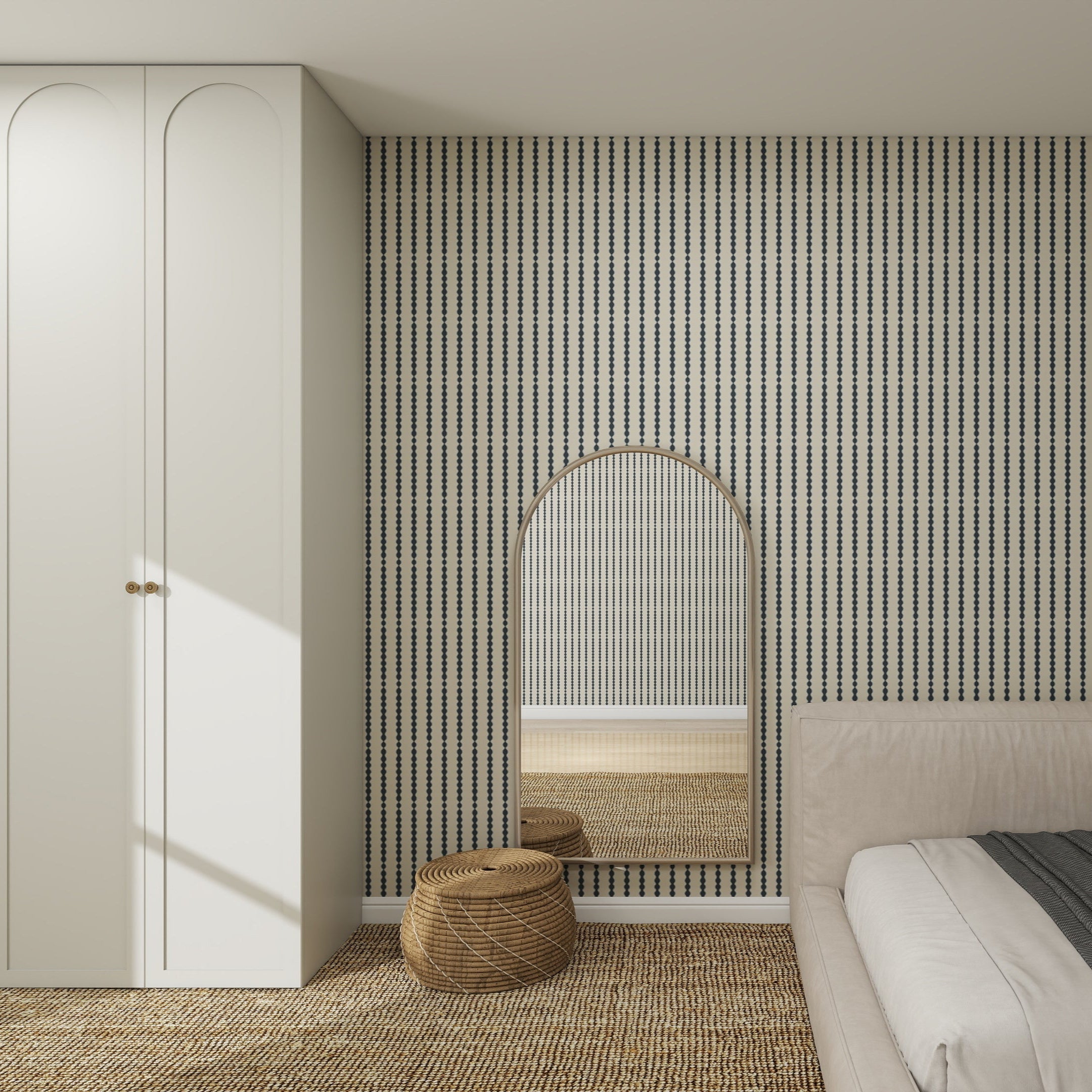 A modern bedroom features Little Abacus Stripe Denim Wallpaper, a large arched mirror, a woven round pouf, a white wardrobe, and part of a beige bed with textured carpet on the floor.