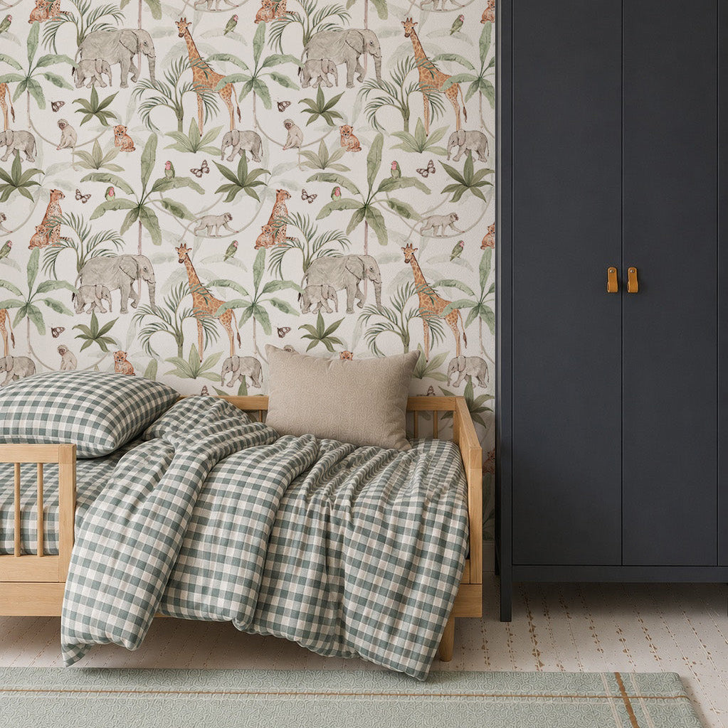 A cozy kids’ room features a small wooden bed with checkered bedding, gray pillow, dark wardrobe, and vibrant African Safari Wallpaper showcasing elephants, giraffes, and birds. A blue pendant lamp hangs overhead.