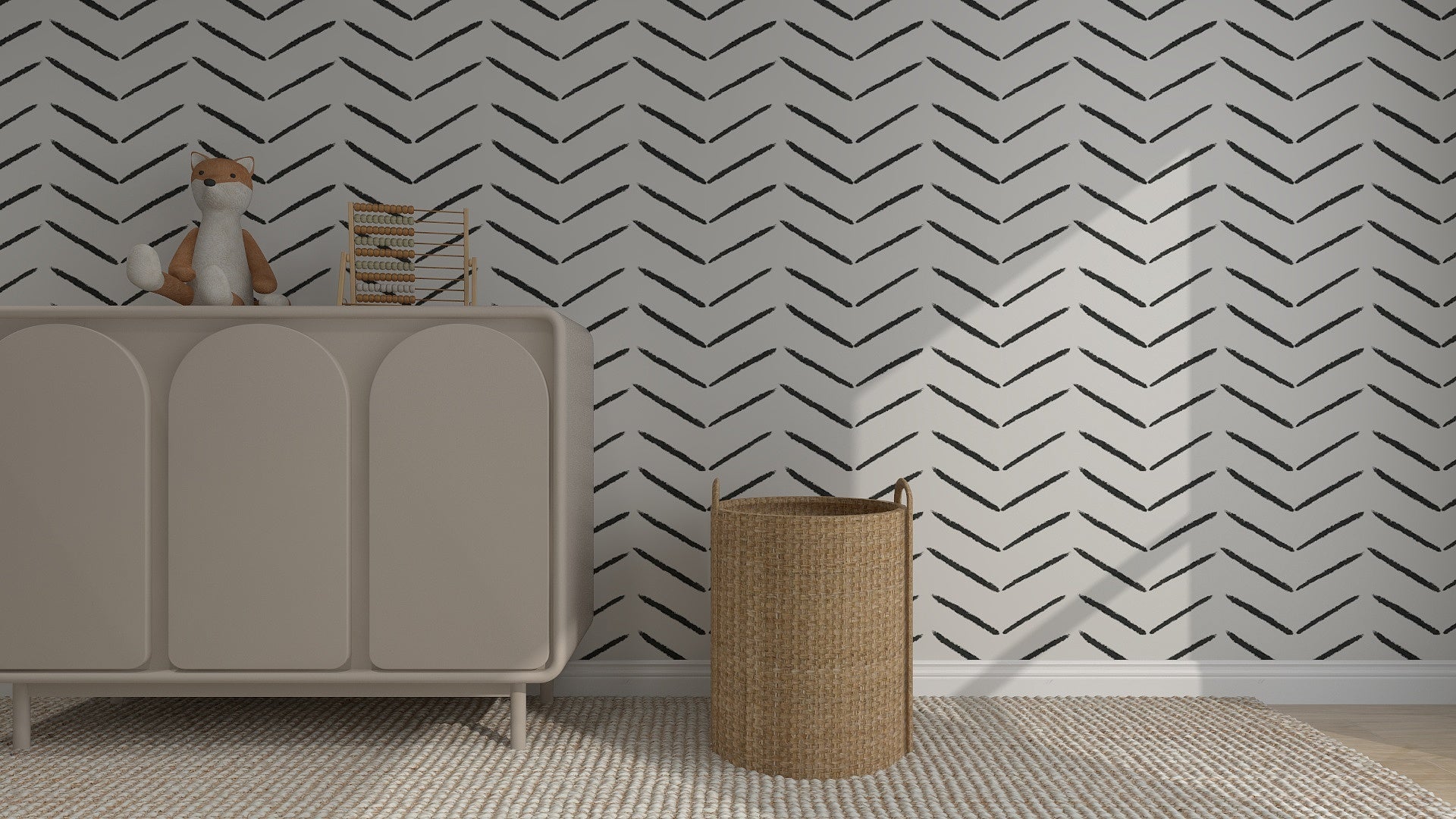 A modern nursery features a light beige dresser with a plush fox toy and an abacus, a woven basket on the floor, and Charcoal Herringbone Wallpaper | Sample on the wall. A textured rug covers the wooden floor.