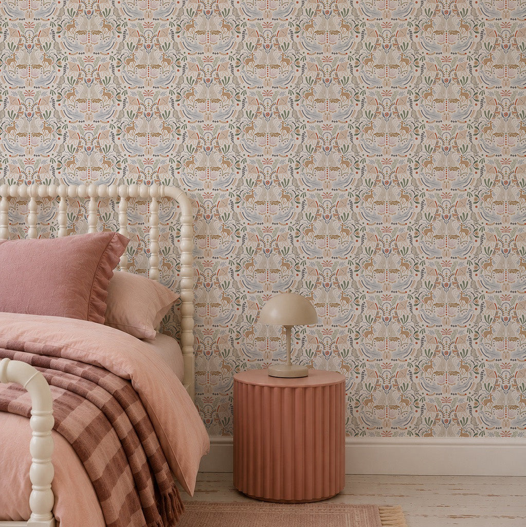 A cozy bedroom featuring the Creatures Great and Small Wallpaper in soft pastels, a cream spindle bed, pink and beige bedding, plus a round ribbed bedside table with a modern lamp for a whimsical touch.