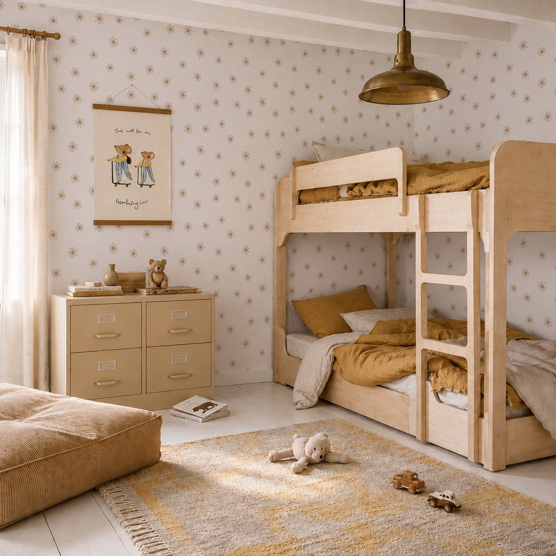 A cozy children’s bedroom with wooden bunk beds, Daisy Floral Wallpaper, sheer-curtained window, dresser, large floor cushion, plush toys on the rug, all in warm beige and gold tones.
