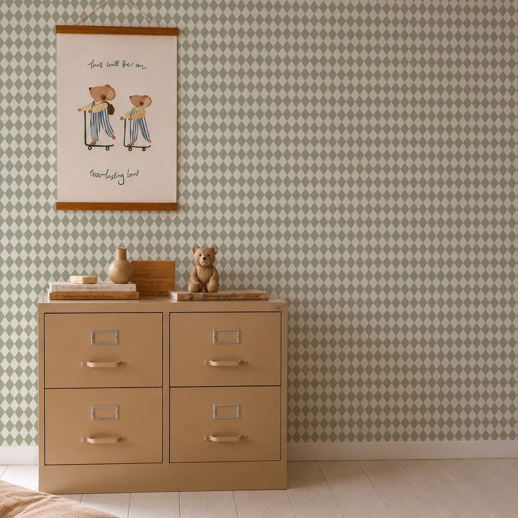 A beige dresser with silver handles stands against Diamond Dancer Wallpaper, Green. On top are a teddy bear and decorative vases. Above hangs a framed illustration of two bears in stripes. A rug rests on the light wood floor.