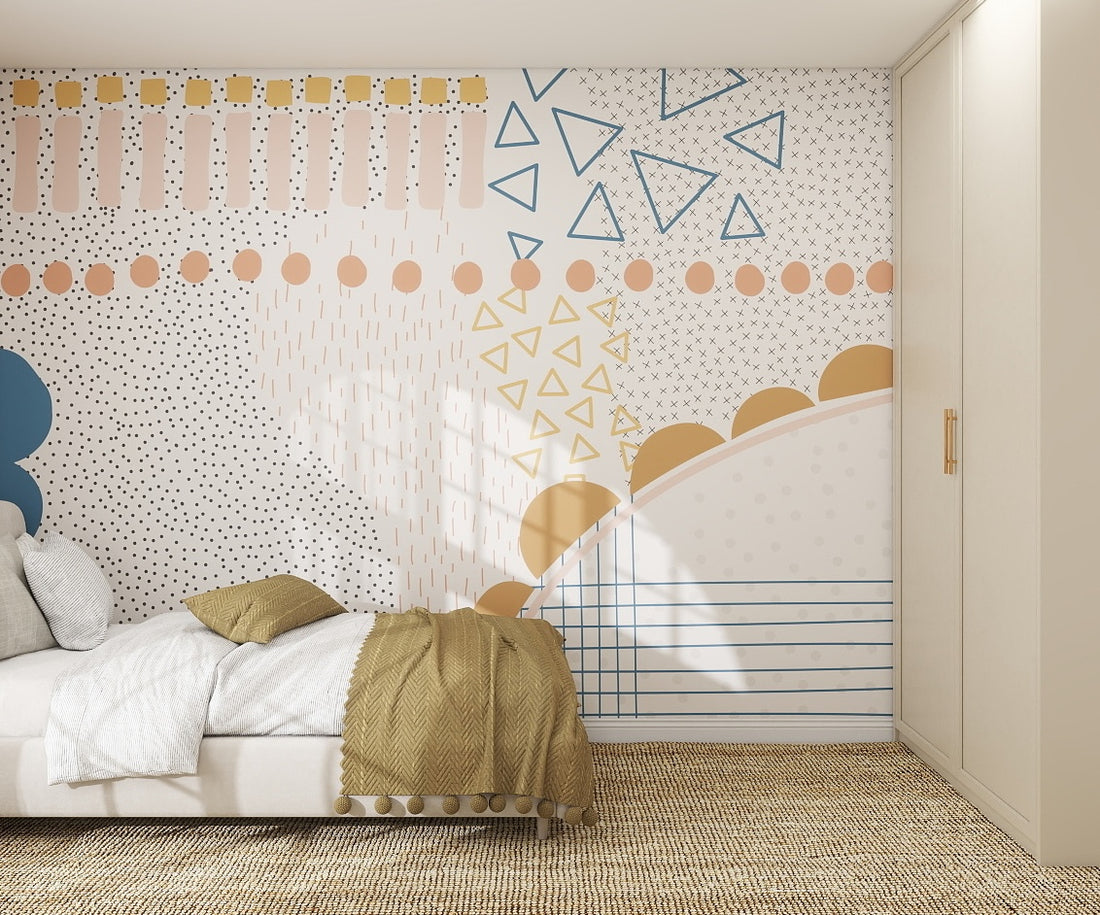 A modern bedroom features a bed with white and mustard bedding, a beige woven rug, and the Evie Abstract Wallpaper Mural in blue, gold, and peach tones on the wall. A closed wardrobe stands to the right.