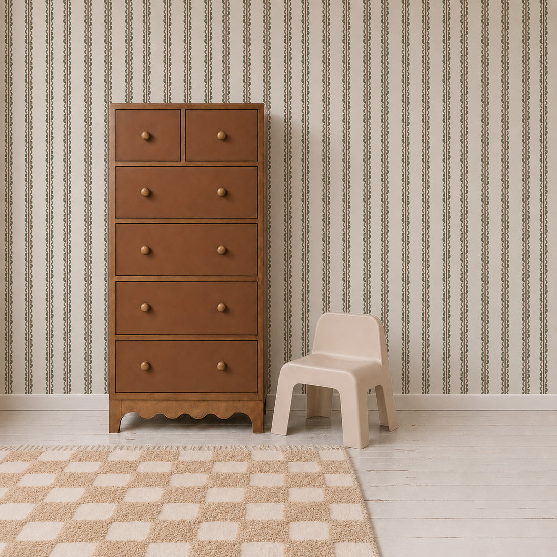 A tall brown dresser with six drawers stands next to a small beige plastic chair, on a white wood floor with a beige checkered rug and Folk Scallop Stripe Wallpaper in Olive & Mocha in the background.