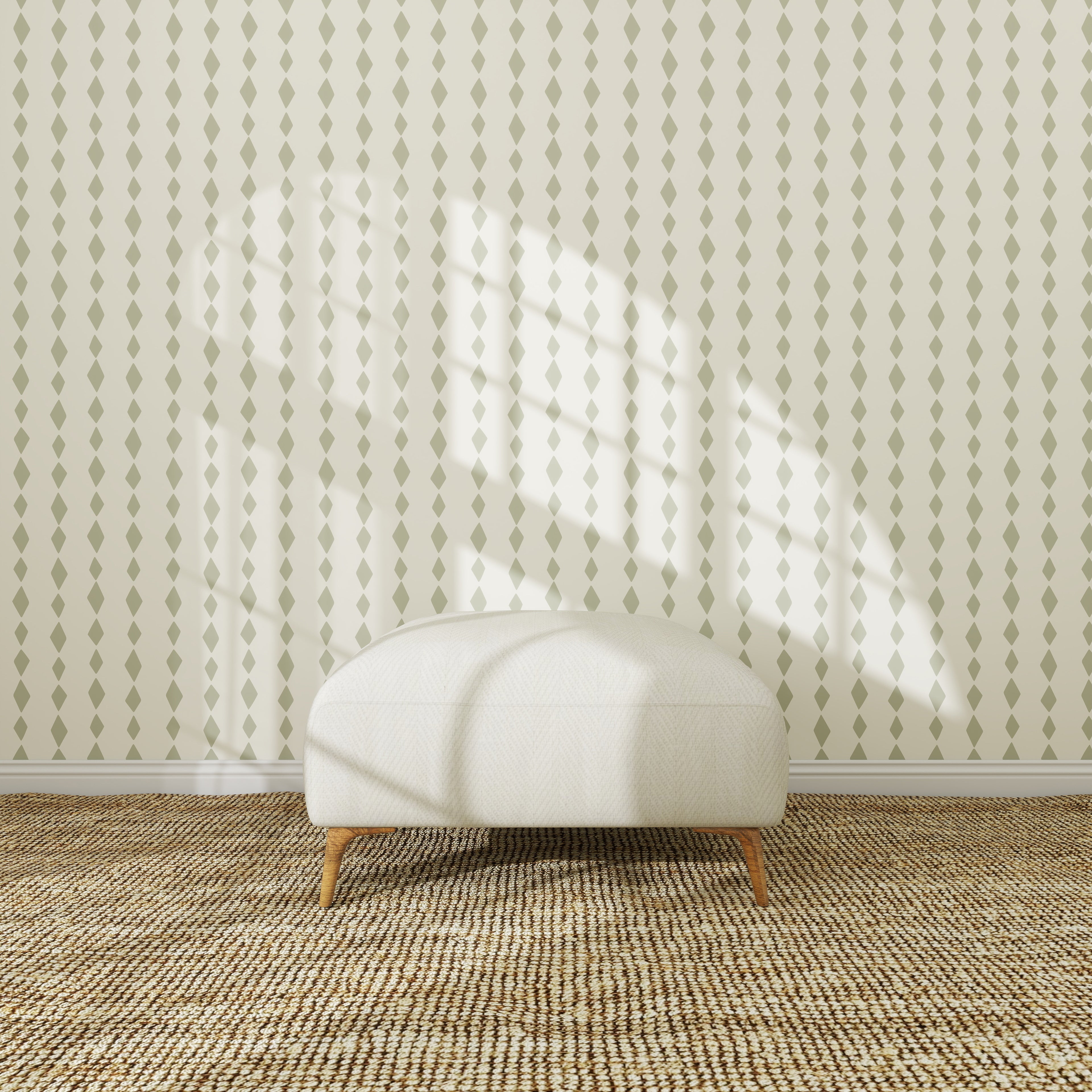 A white upholstered ottoman with wooden legs sits on a woven carpet in front of the Jolly Jester Wallpaper Repeat Sage Green, as sunlight casts window-shaped shadows across the scene.