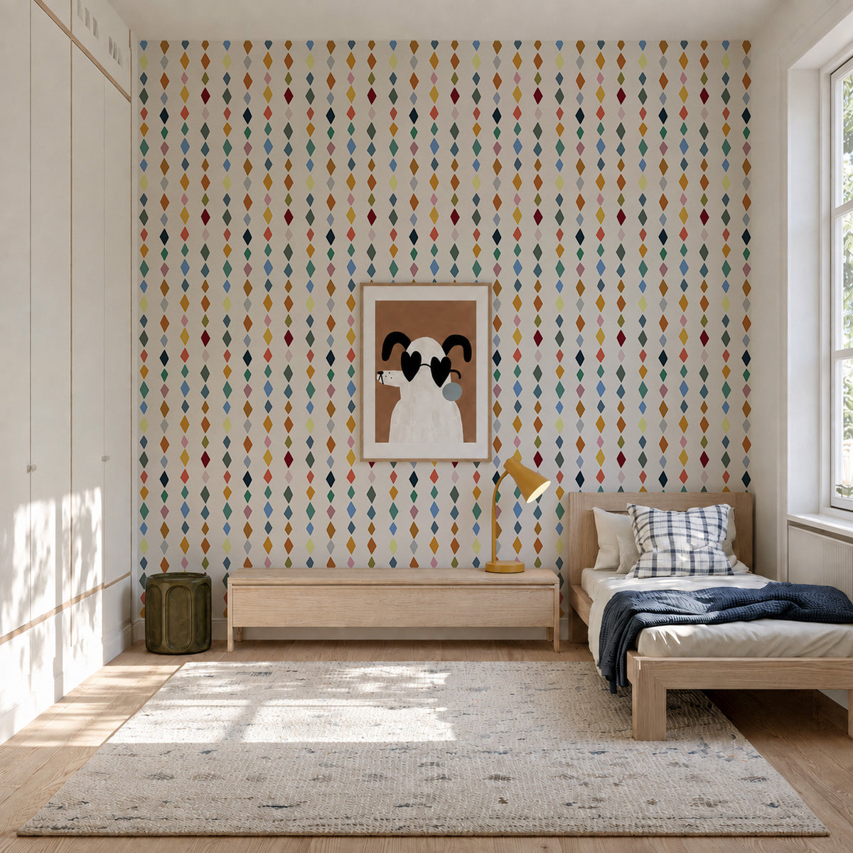 A bedroom wall featuring colorful Jolly Jester Wallpaper, Multi, with a repeating vertical diamond pattern, centered with a framed illustration of a dog.