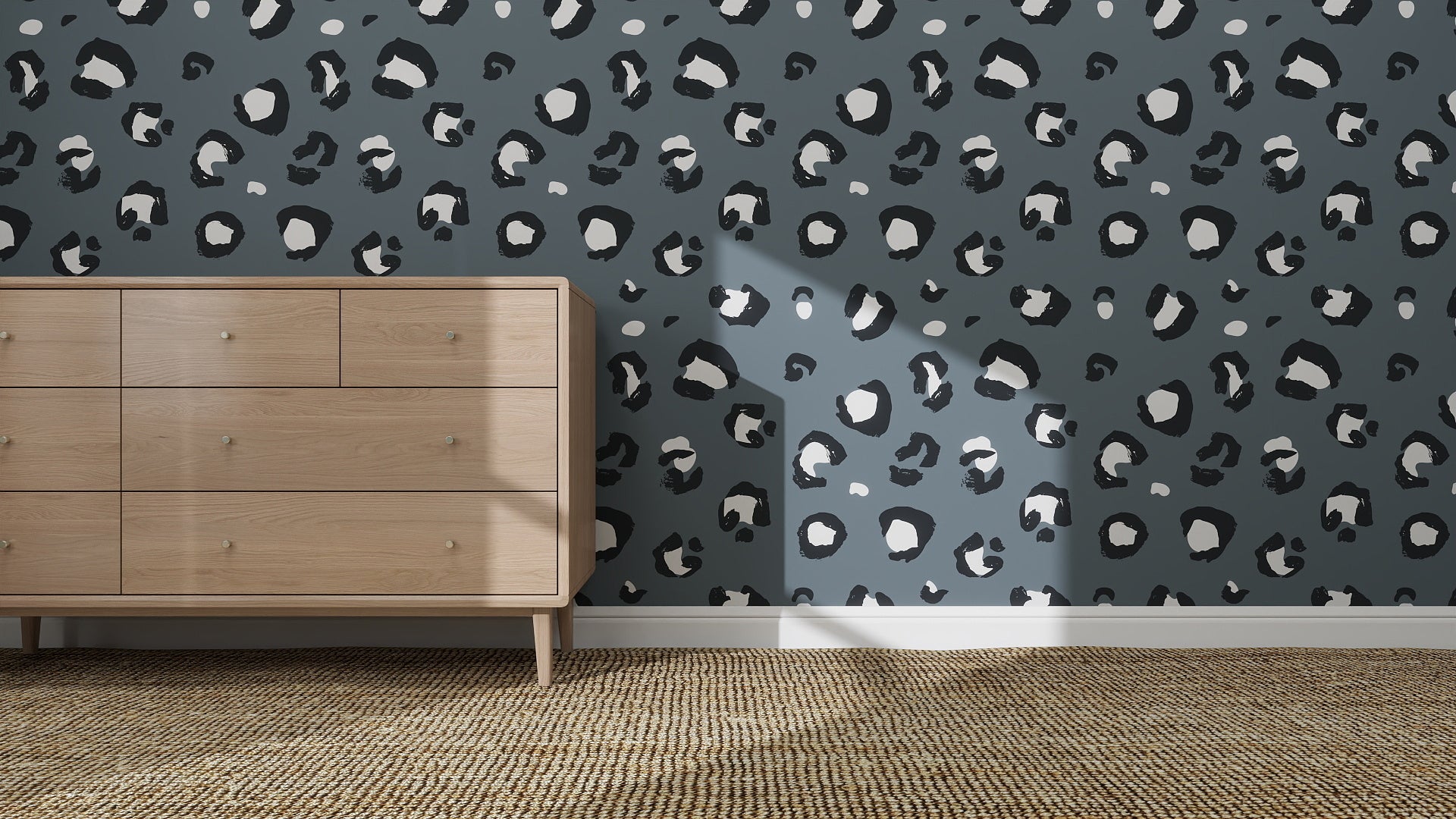 A wooden dresser sits on a woven rug next to a wall covered in Blue Leopard Print Wallpaper | Sample, with sunlight casting shadows that highlight the bold, stylish look of the room.