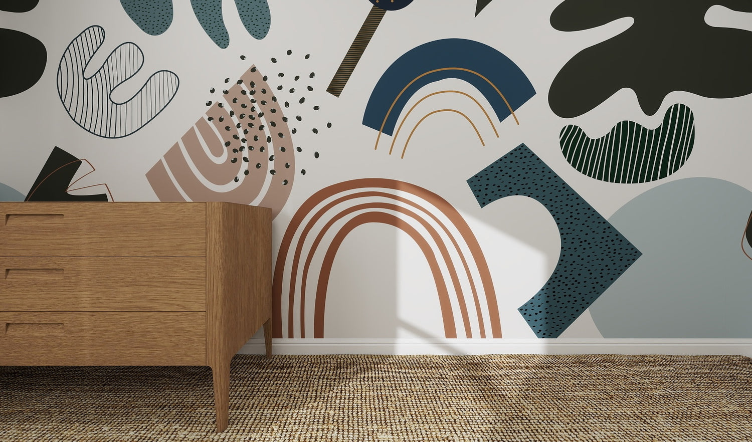A wooden dresser stands on a woven rug by a white wall decorated with the Little Erin Abstract Wallpaper Mural | Blue, featuring bold muted shapes in blue, brown, green, and black for a modern artistic feel.