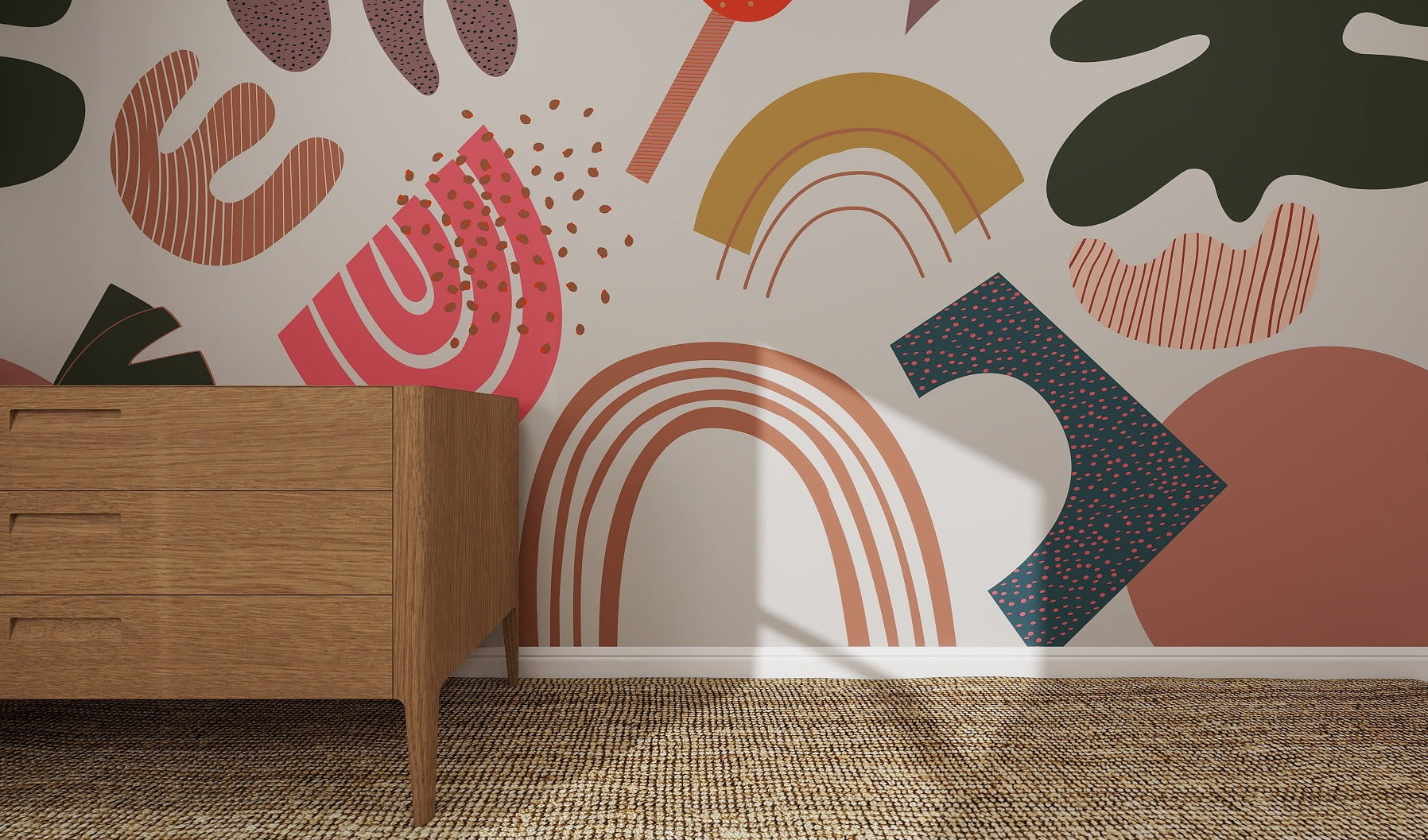A wooden dresser stands on a woven rug beside a wall decorated with the Little Erin Abstract Wallpaper Mural, featuring colorful abstract shapes, rainbows, and vibrant pink, yellow, green, orange, and blue patterns.