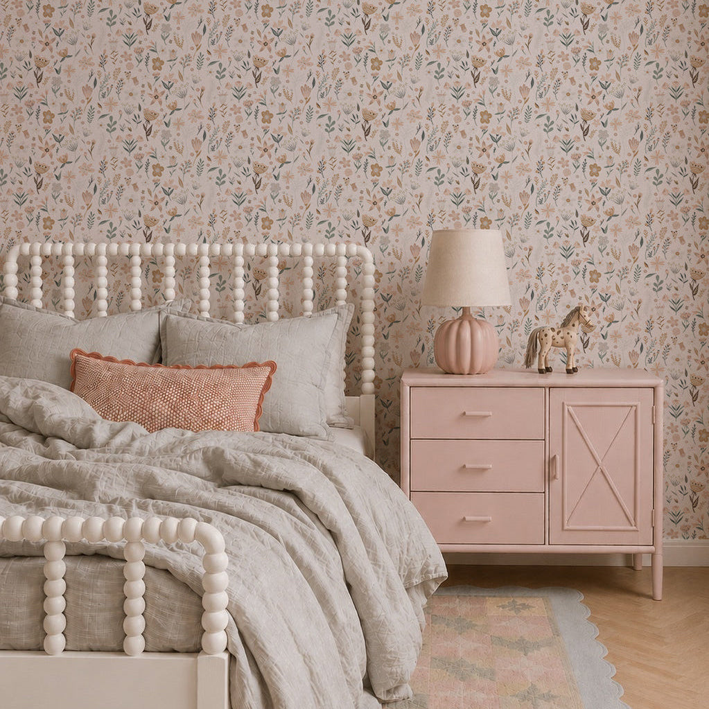 A cozy bedroom features a light wood bed, soft gray bedding, and pastel decor. Millie Floral Wallpaper and a pink nightstand add gentle charm, while a toy giraffe rests beneath the warm glow of a pink lamp.