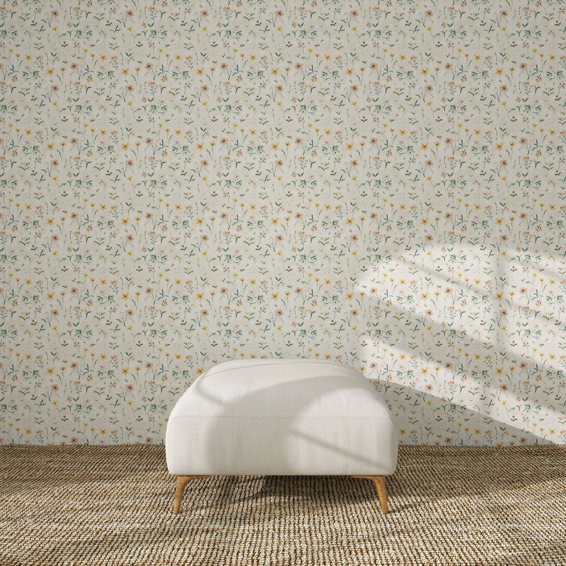 A white ottoman with wooden legs sits on a woven rug before a wall decorated with Morning Meadow Wallpaper, as sunlight casts gentle window shadows across the scene.