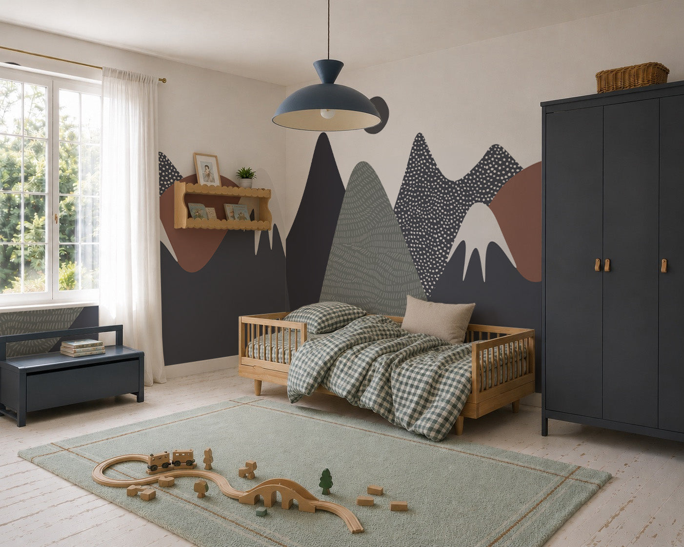 A cozy kids’ bedroom with a wooden bed, checkered bedding, Mountain Mural wall art, dark wardrobe, green rug scattered with wooden toys, bench, and window with sheer curtains welcoming sunlight—a true mountain oasis in home decor.