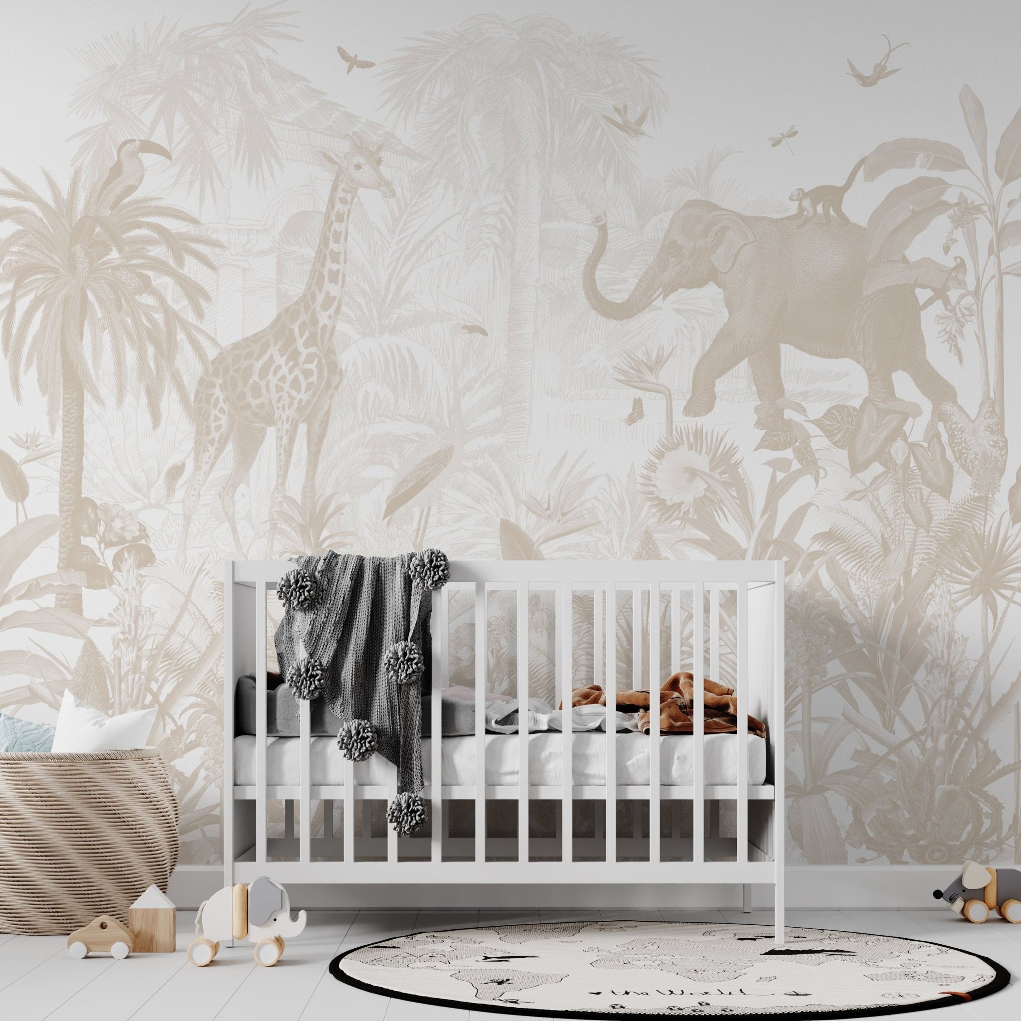 A white crib with a blanket sits in a childrens room decorated with the Magic Jungle Wallpaper Mural, which features a giraffe, elephant, and tropical plants in soft beige hues. A basket, rug, and toys complete the cozy nursery.