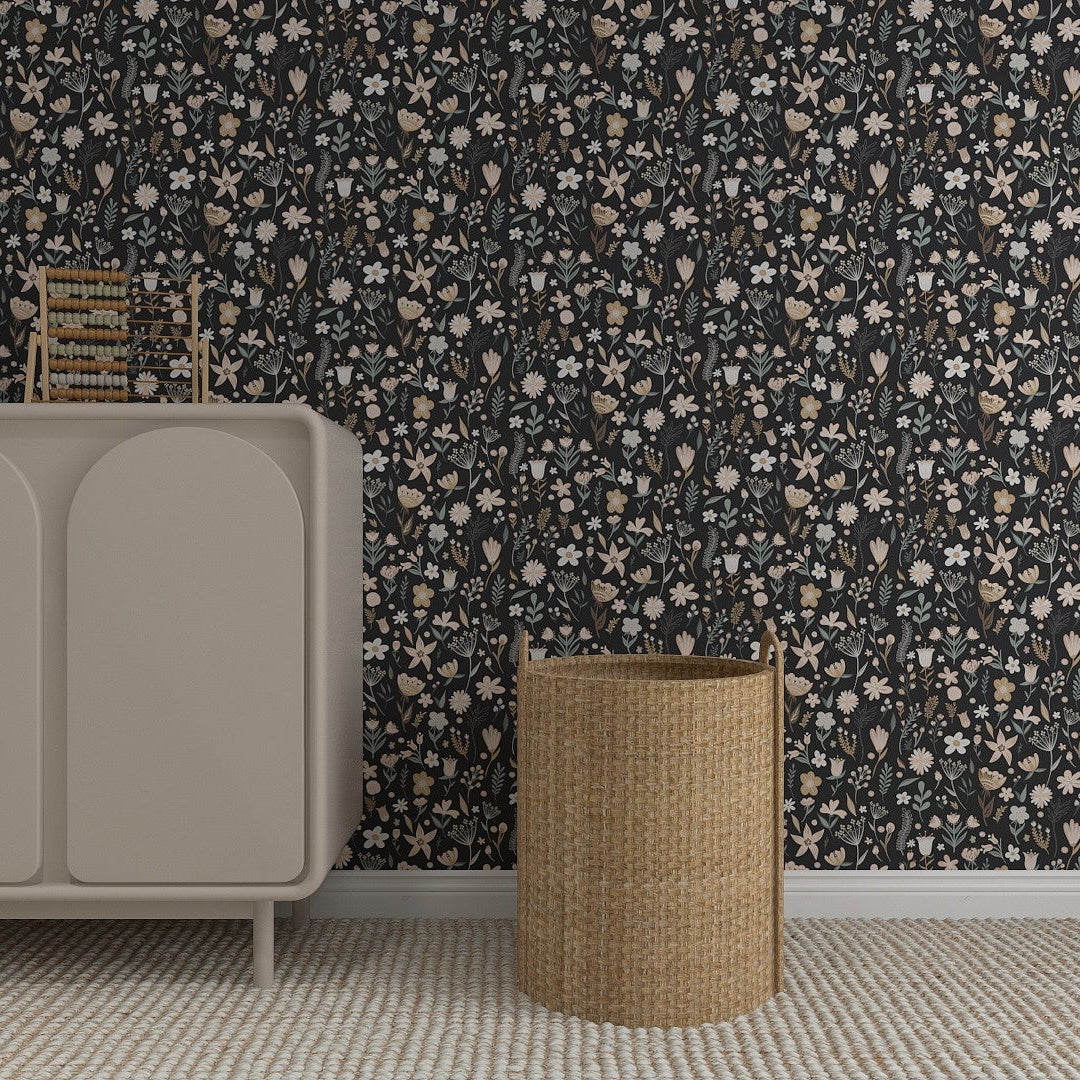 A beige cabinet with a toy fox and books stands against the Millie Floral Wallpaper Repeat Pattern in Charcoal, with a woven basket nearby on a light textured rug, creating a charming update.