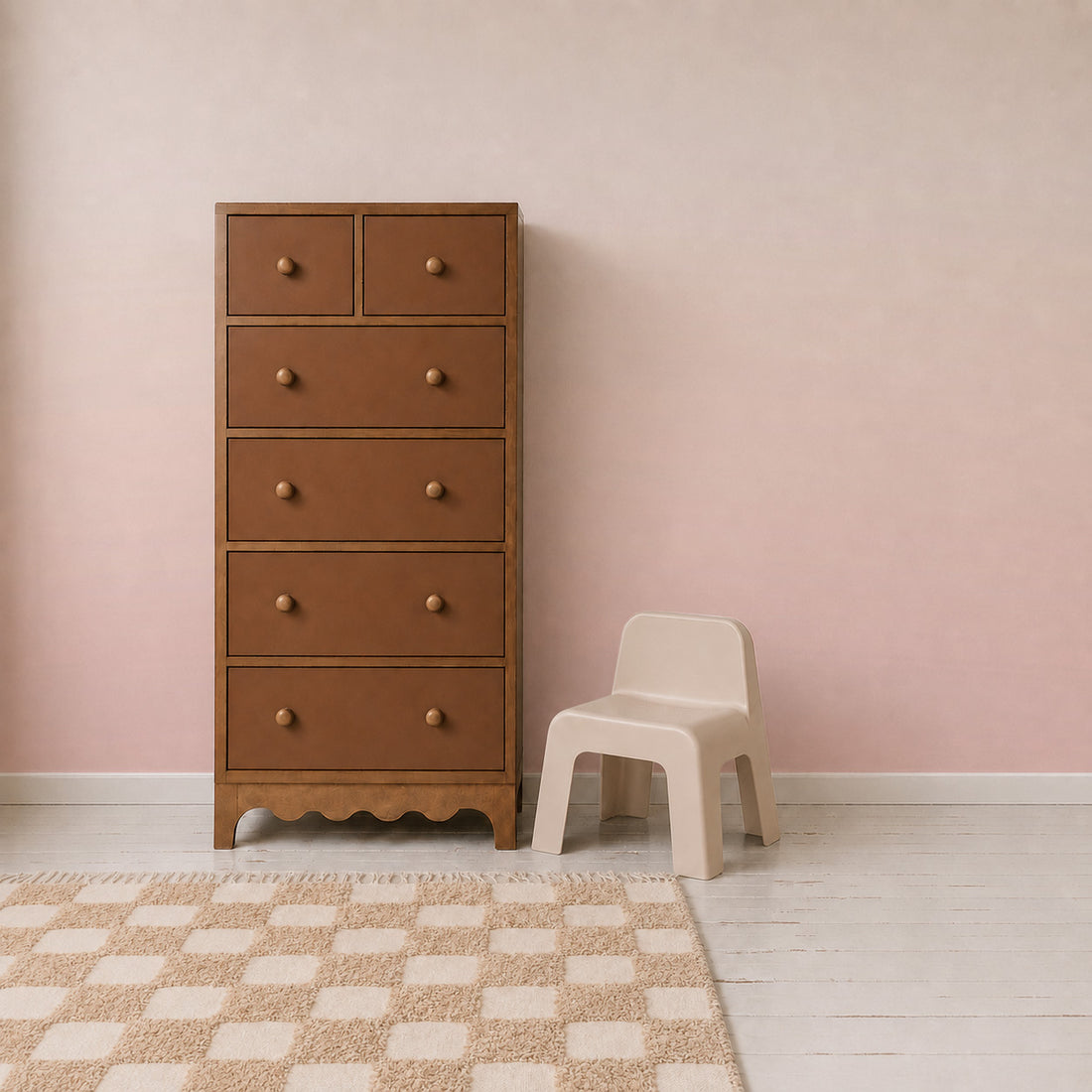 A tall brown dresser with six drawers stands next to a small beige chair. The room features a checkered rug, light wood floor, and an Ombre Mural, Pink that adds playful wall decor to the pink gradient wall.
