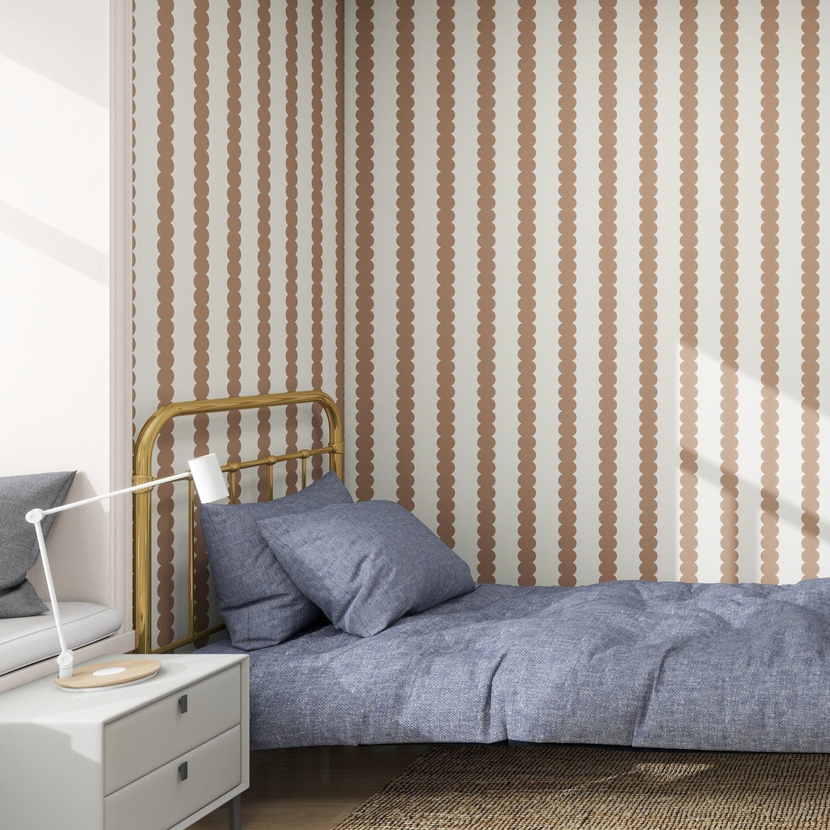 A minimalist bedroom features a single bed with a blue quilt and two pillows, walls adorned with munks and mes Scallop Stripe Wallpaper Latte, a white bedside table with a modern lamp, and a woven rug covering the wooden floor.