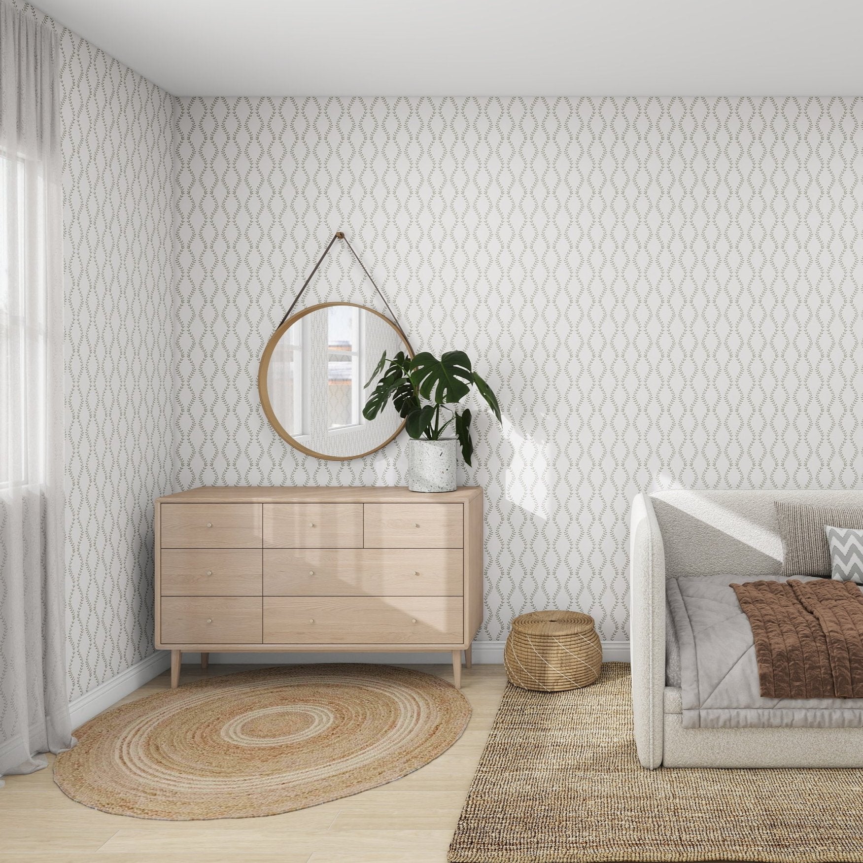 A cozy space features Vintage Vines Wallpaper Repeat Pattern by munks and me, light patterns, a wooden dresser with a potted plant and round mirror above, a textured rug near a wicker basket, and a couch with a brown throw. Natural light enhances the elegance through the window.